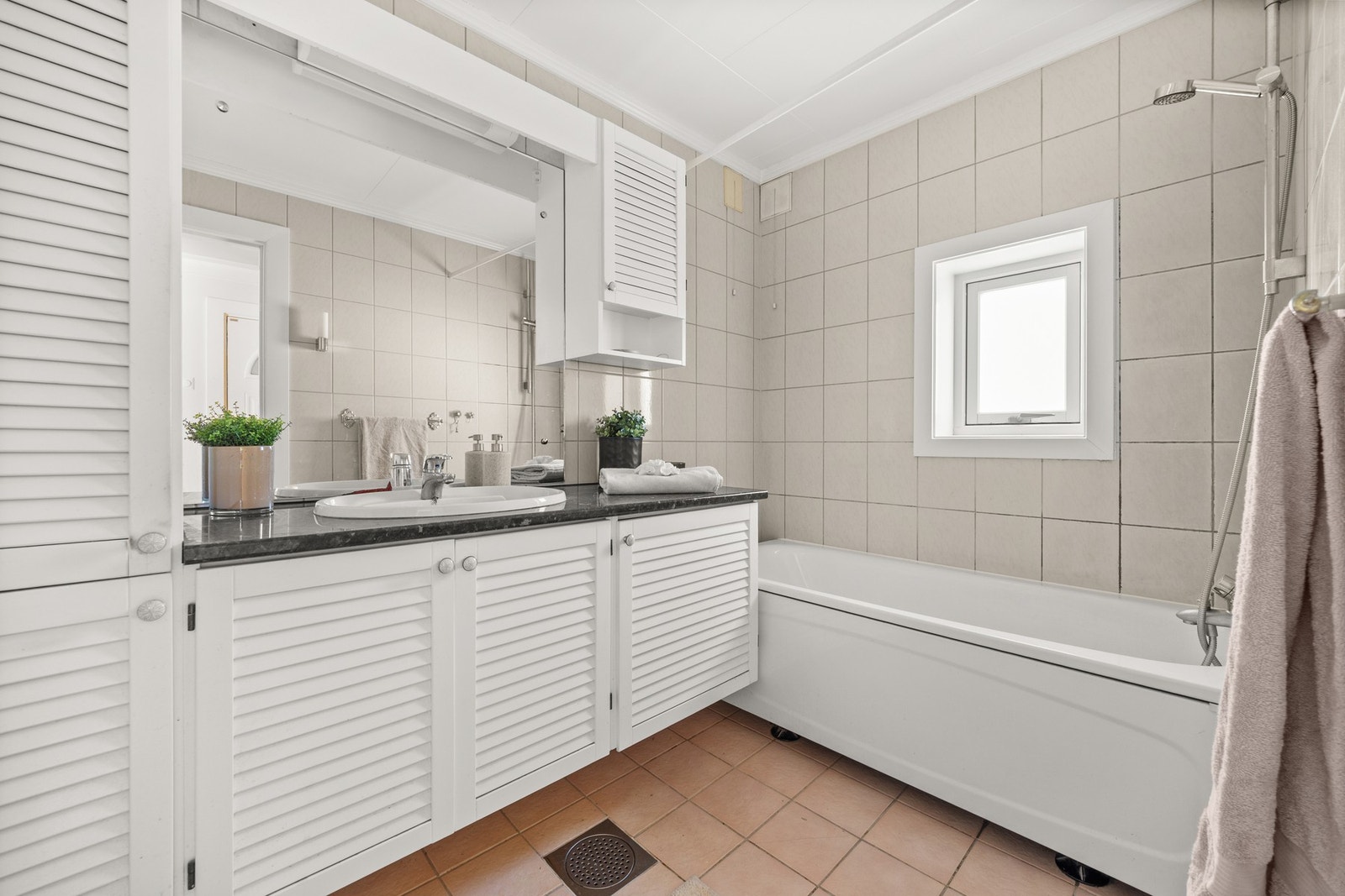 Pent flislagt baderom. Badet har gulvvarme og er utstyrt med vegghengt servantinnredning med skuffer Galleribilde