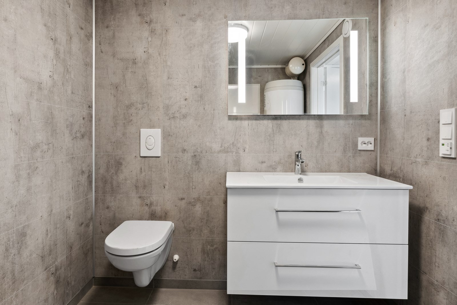 Bad inneholder dusj, vegghengt wc, servant med skuffer og tilkobling til vaskemaskin. Galleribilde