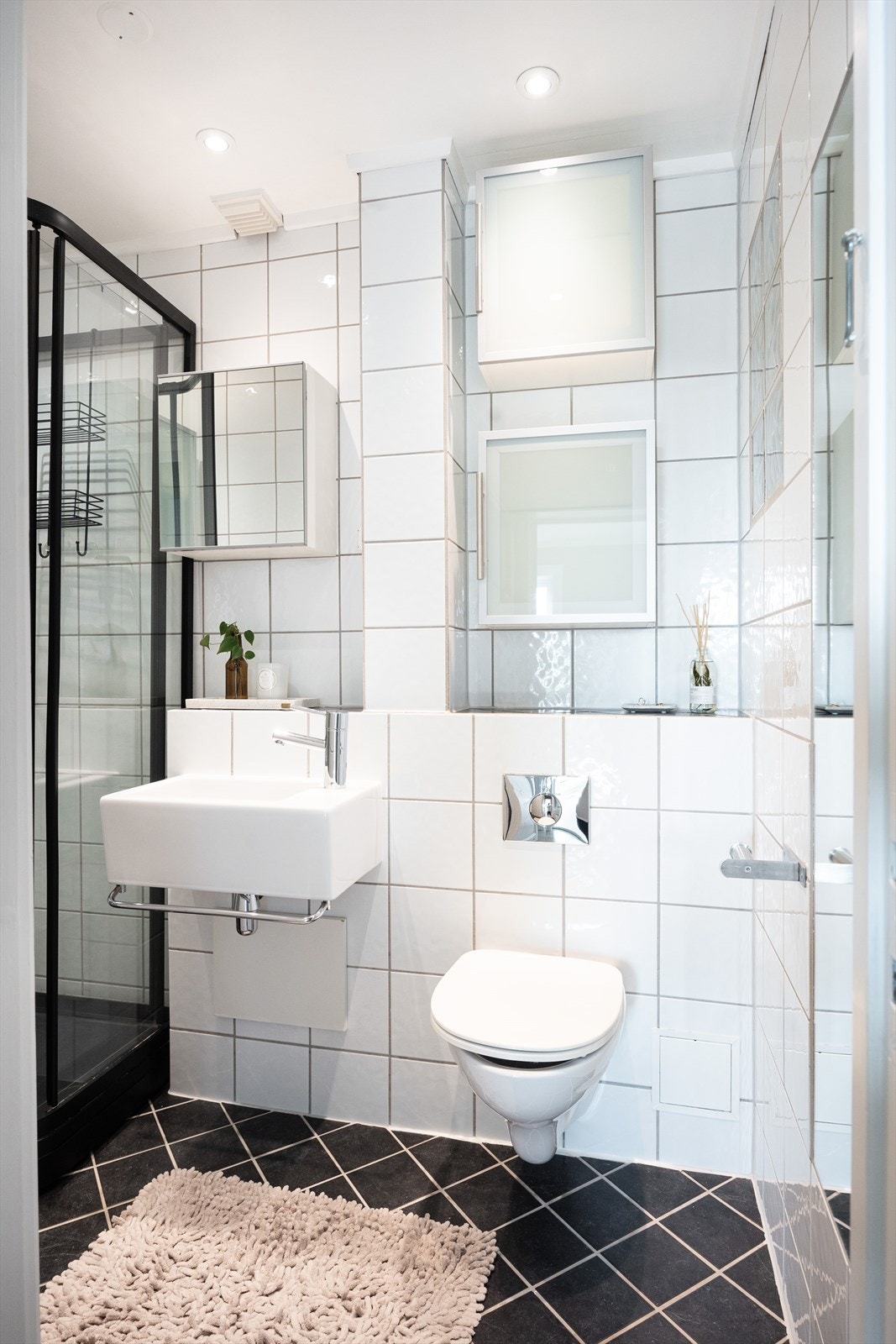 Flislagt bad med flis på vegg og gulv, malte plater i taket. Rommet er innredet med dusjkabinett, servant og vegghengt toalett. Galleribilde