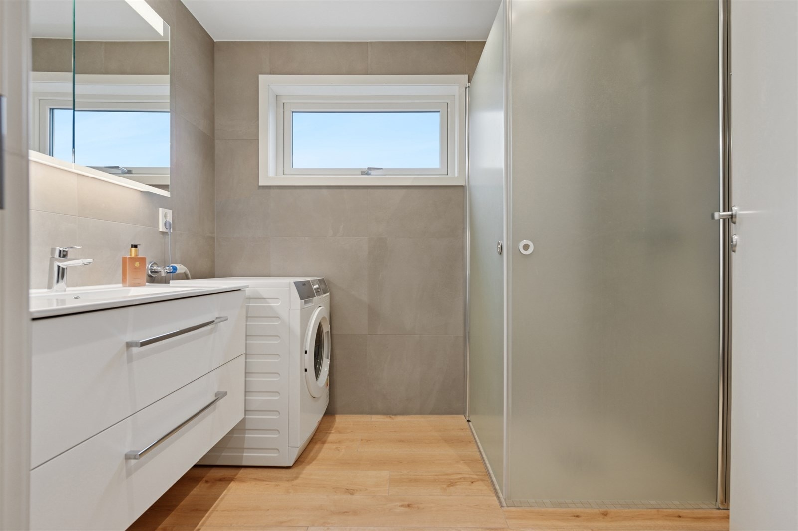 Baderommet er totalrenovert i 2022 fra grunnen opp | Fliser på vegger og gulv med varmekabler | Dusjhjørne har regndusj og innfellbare glassdører. Galleribilde