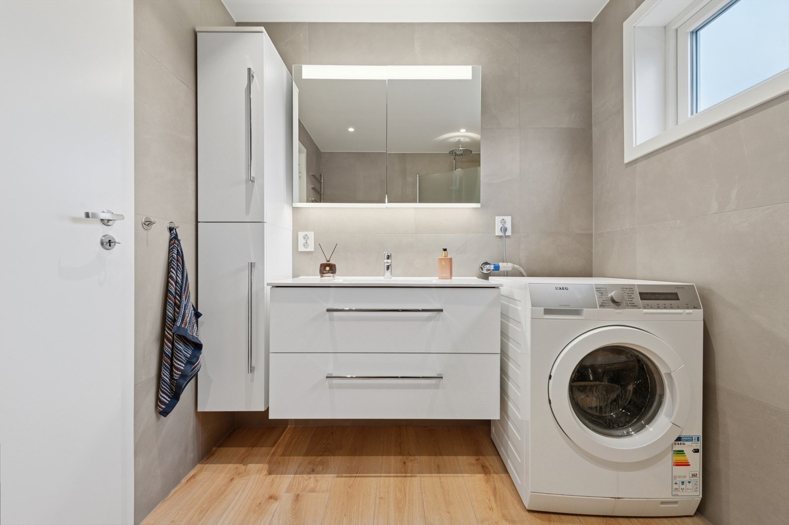 Tilstrekkelig med oppbevaring for håndklær og toalettartikler | Speilskap med integrert belysning | Opplegg til vaskemaskin. Galleribilde