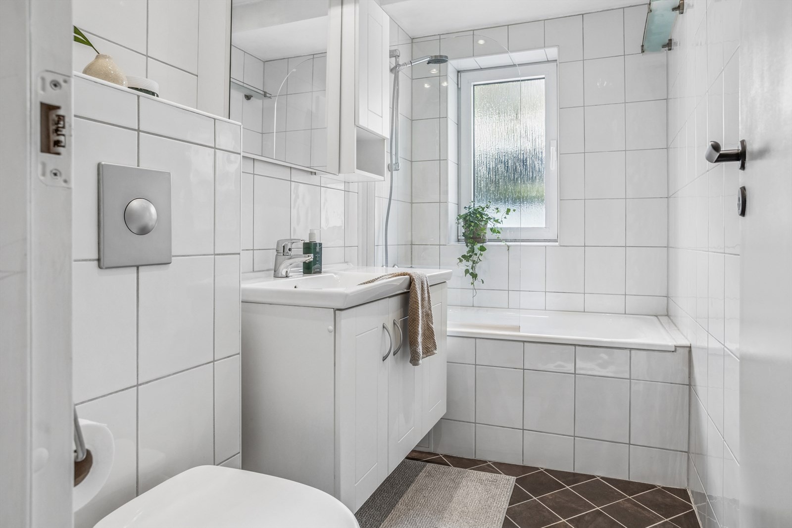 Pent bad i klassisk utførelse. Badet inneholder toalett, flislagt badekar og servant/speil med skapinnredning Galleribilde