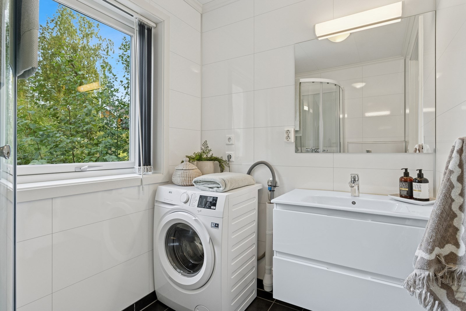 Badet er utstyrt med servantinnredning, vegghengt toalett og dusjkabinett, samt tilrettelagt med plass og opplegg for vaskemaskin. Galleribilde