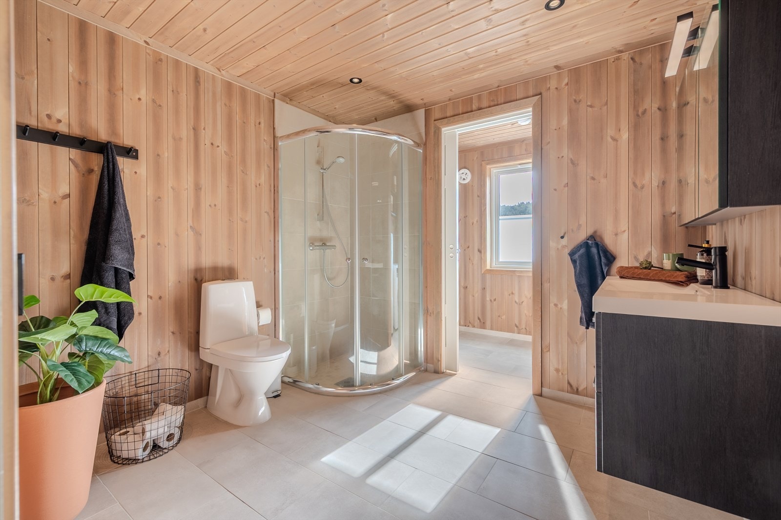 Romslig bad med dusjkabinett, stilren innredning og skyvedør til vaskerom Galleribilde