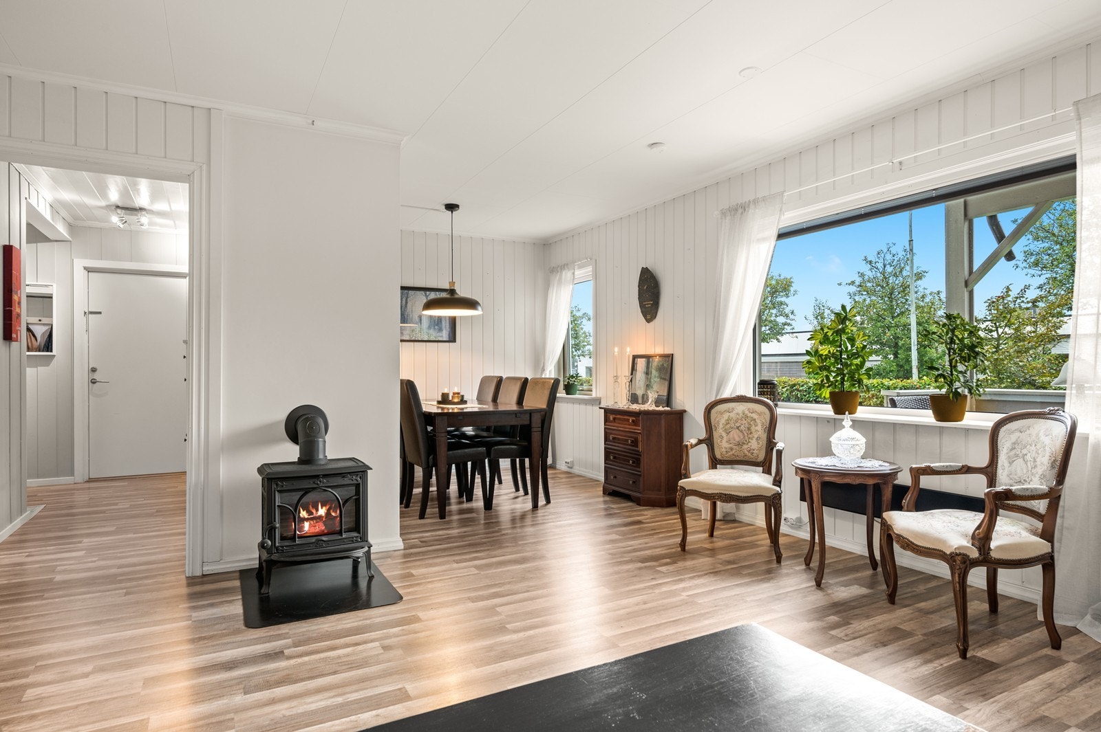 Lys stue, med flere møbleringssoner. Veggen til et tidligere soverom har blitt fjernet, slik at stuen har fått større arealer med plass til spisegruppe Galleribilde