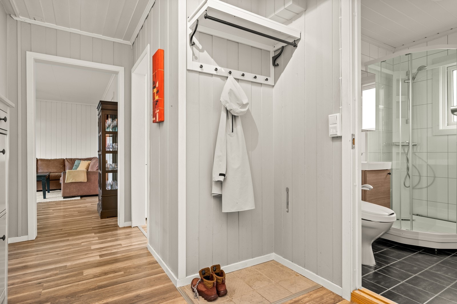 Gang/entré med en praktisk nisje for oppheng av yttertøy, og med et et flislagt område på gulvet for oppstilling av sko Galleribilde