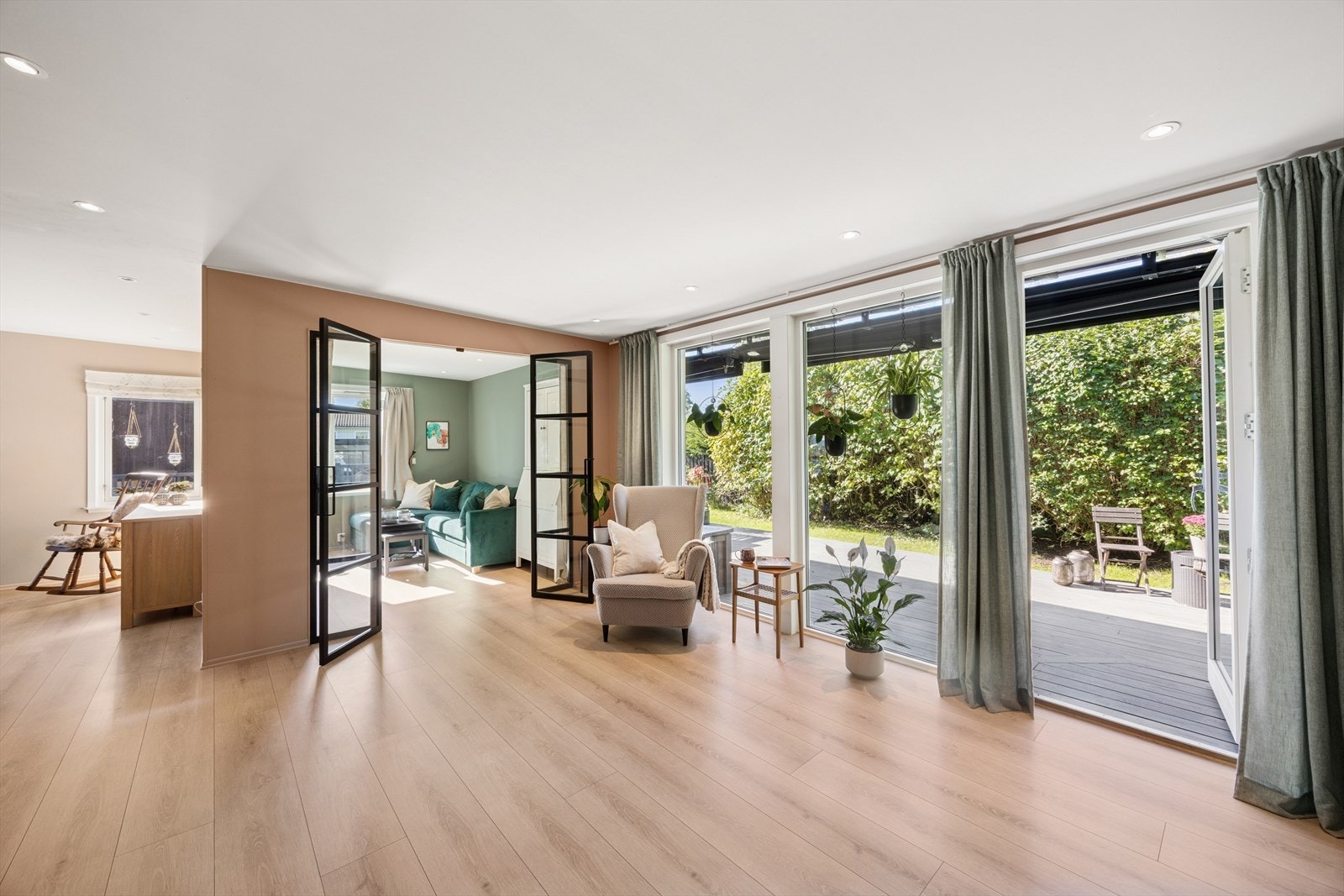 Det er store vindusflater som slipper inn rikelig av naturlig lys, samt utgang til uteplass og hage Galleribilde