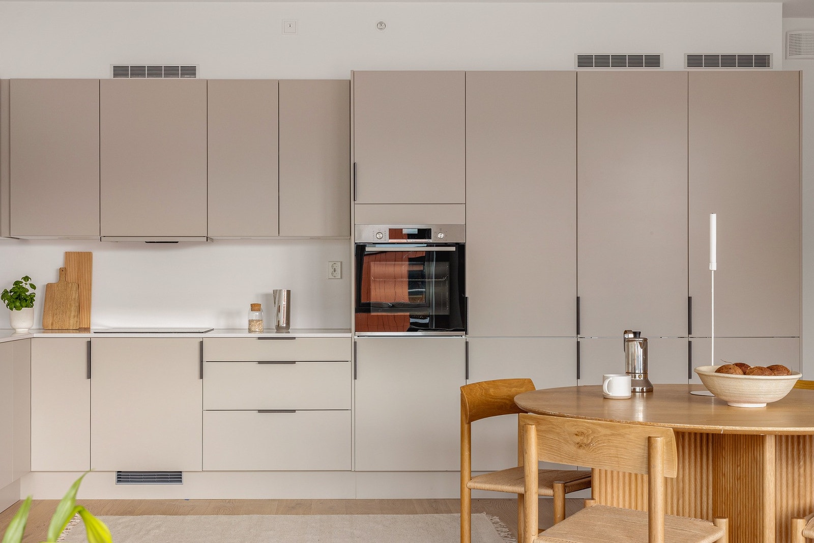 Integrerte hvitevarer bestående av kjøl- og fryseskap i høyskap, stekeovn, platetopp, ventilator og oppvaskmaskin. Galleribilde