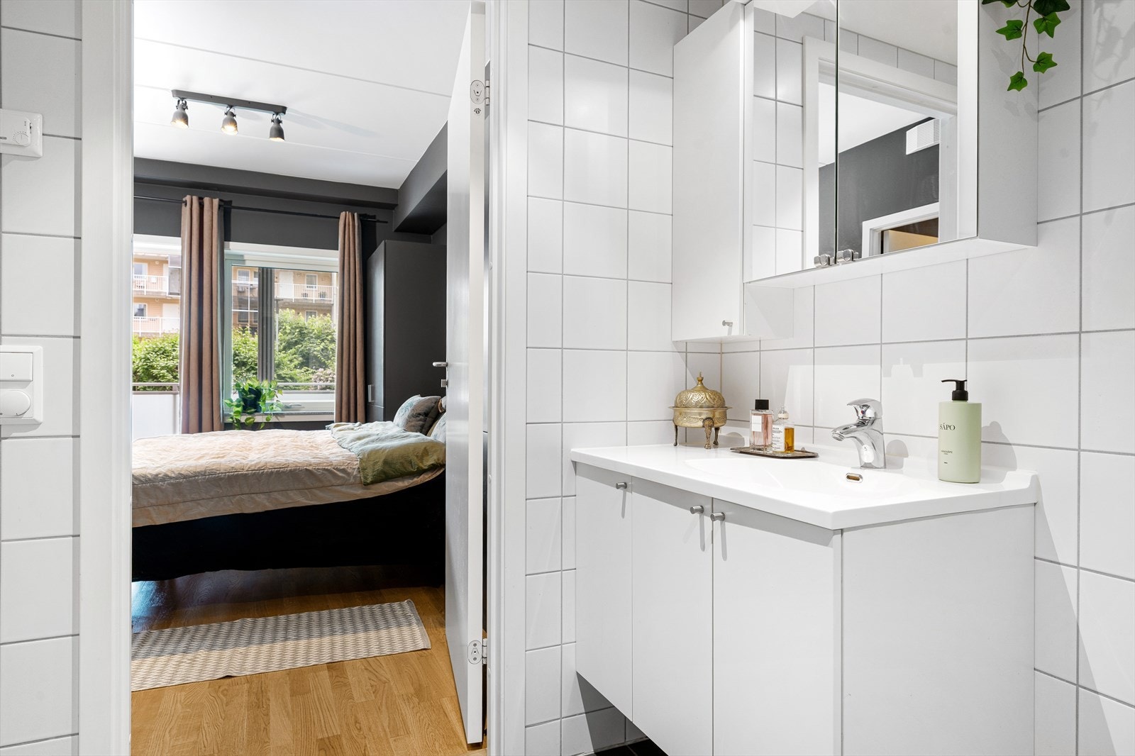Badet har lyse fliser på vegg og mørke fliser på gulv, downlightsbelysning i himling og helservant på baderomsinnredning. Galleribilde