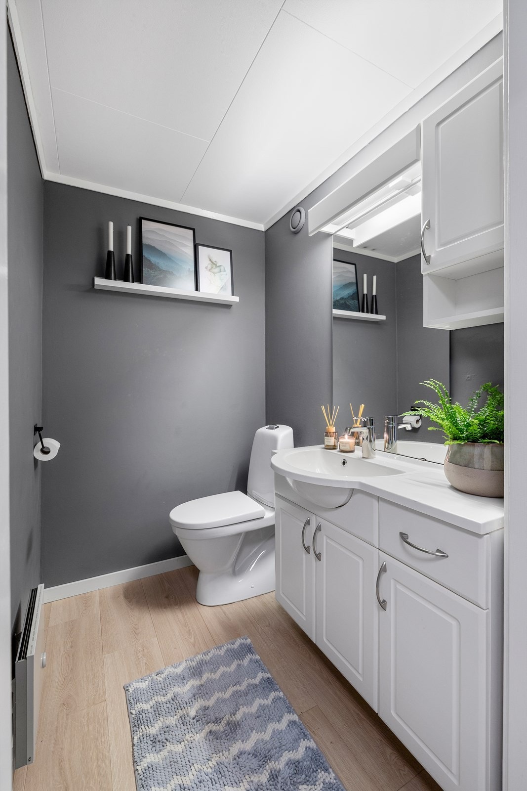 Praktisk toalettrom med gulvstående toalett og innredning med servant Galleribilde