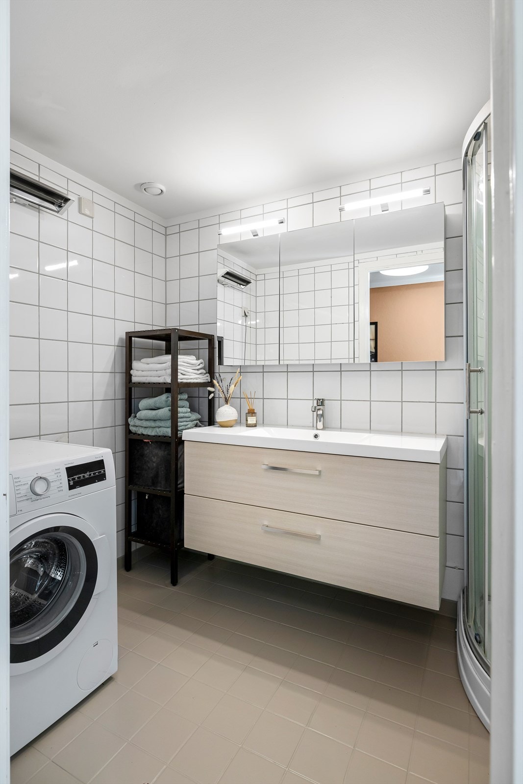 Det er innredet med dusjkabinett, opplegg for vaskemaskin og hvit innredning med heldekkende porselensvask Galleribilde