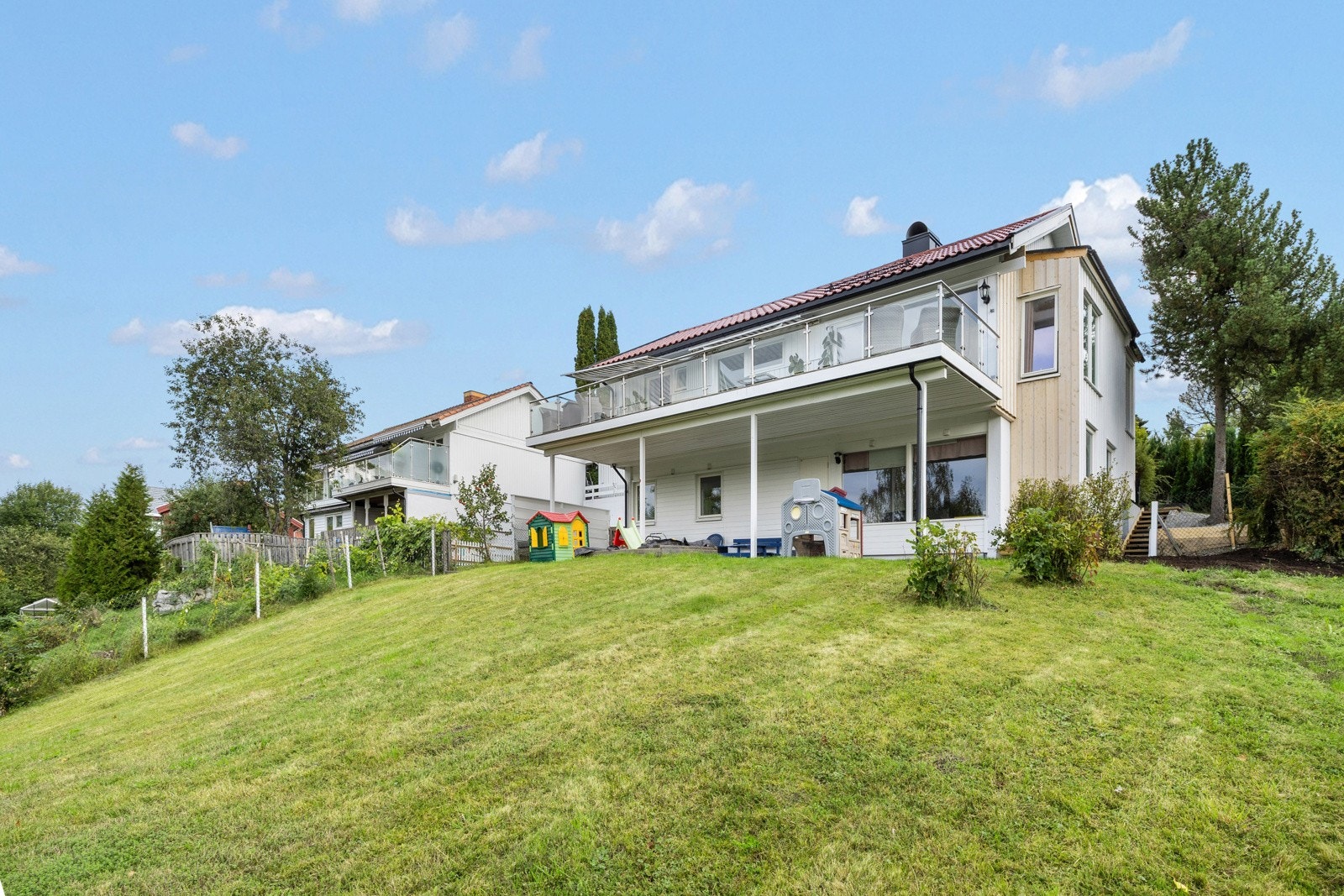 Tomten fremstår som svært familievennlig med god boltreplass, store gressarealer og flere uteplasser som kan benyttes gjennom hele dagen. Galleribilde