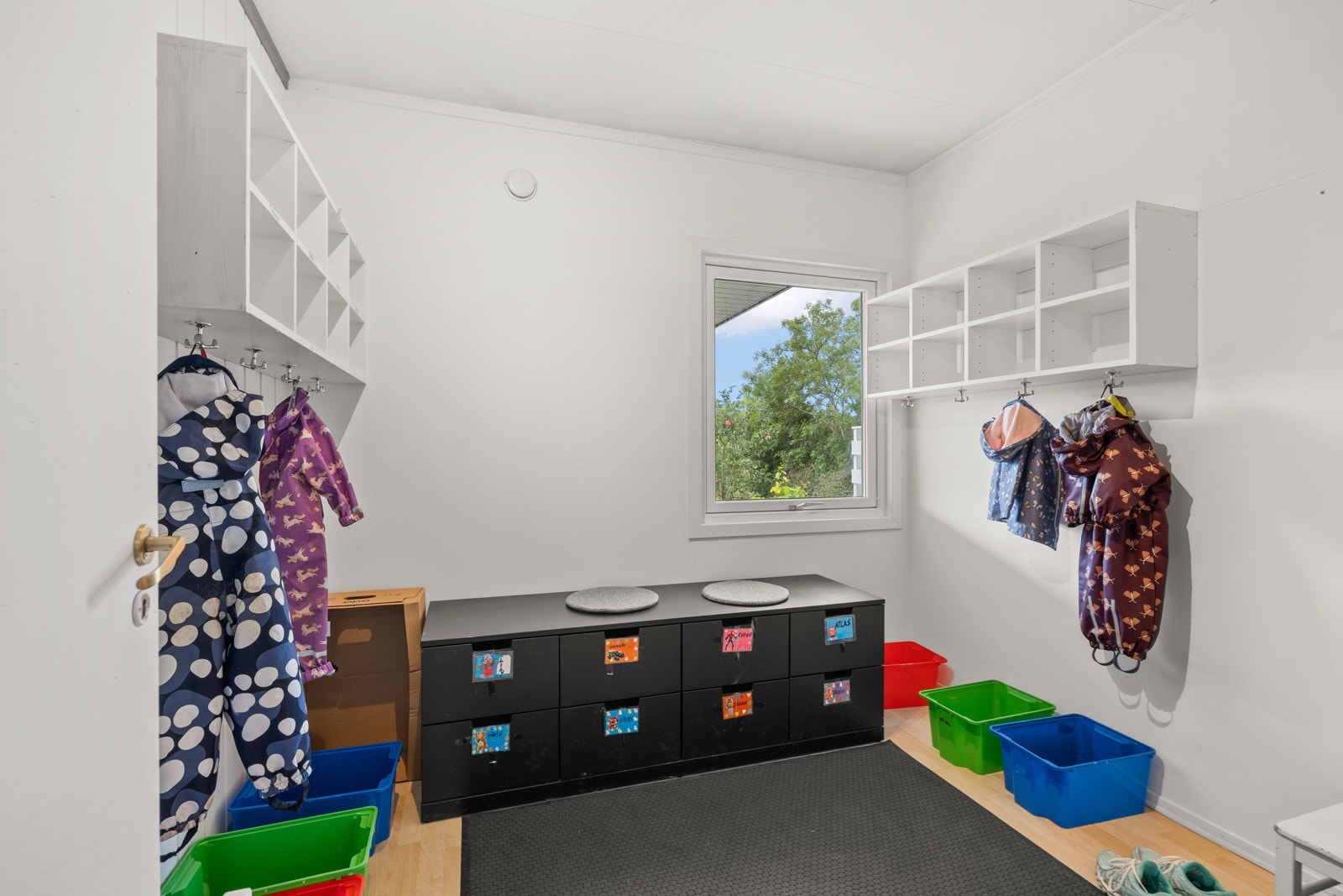 Et av etasjens soverom brukes praktisk som garderoberom for barnas utetøy, med kroker, hyller og oppbevaringsplass som gjør det enkelt å organisere hverdagen. Galleribilde