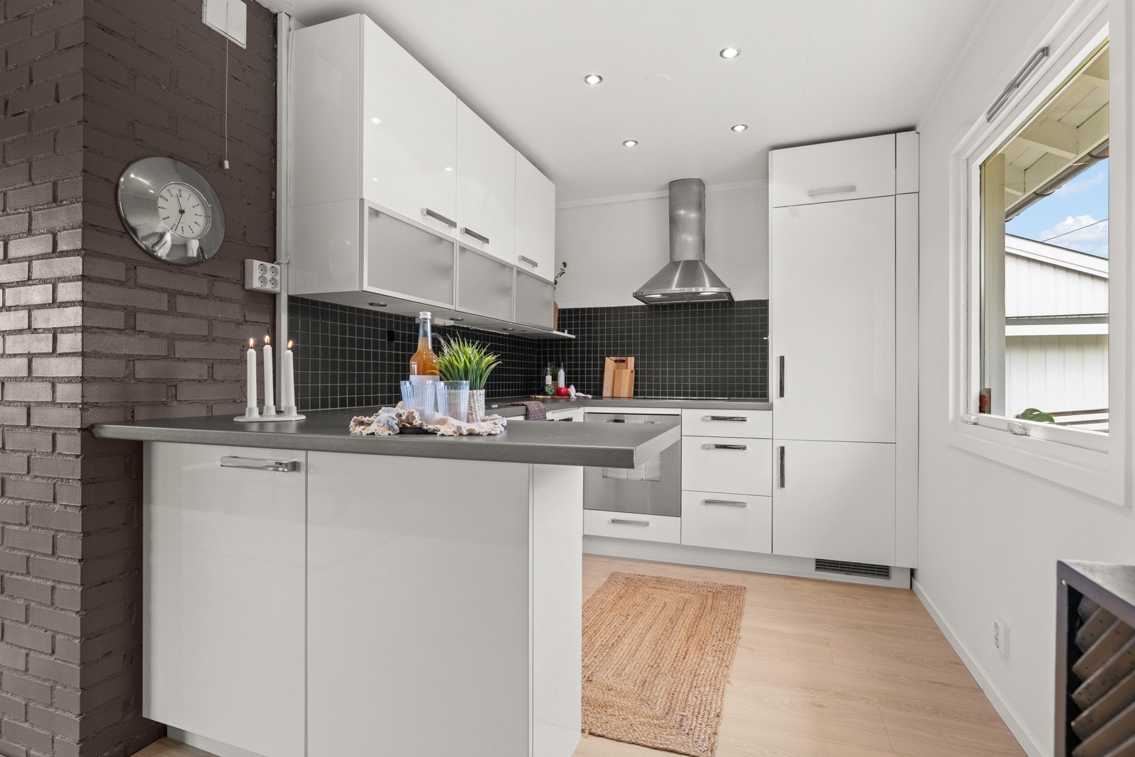 Innredningen har glatte, hvite fronter kombinert med laminat benkeplate med nedfelt stålkum, rillebrett og ettgreps kjøkkenkran. Galleribilde