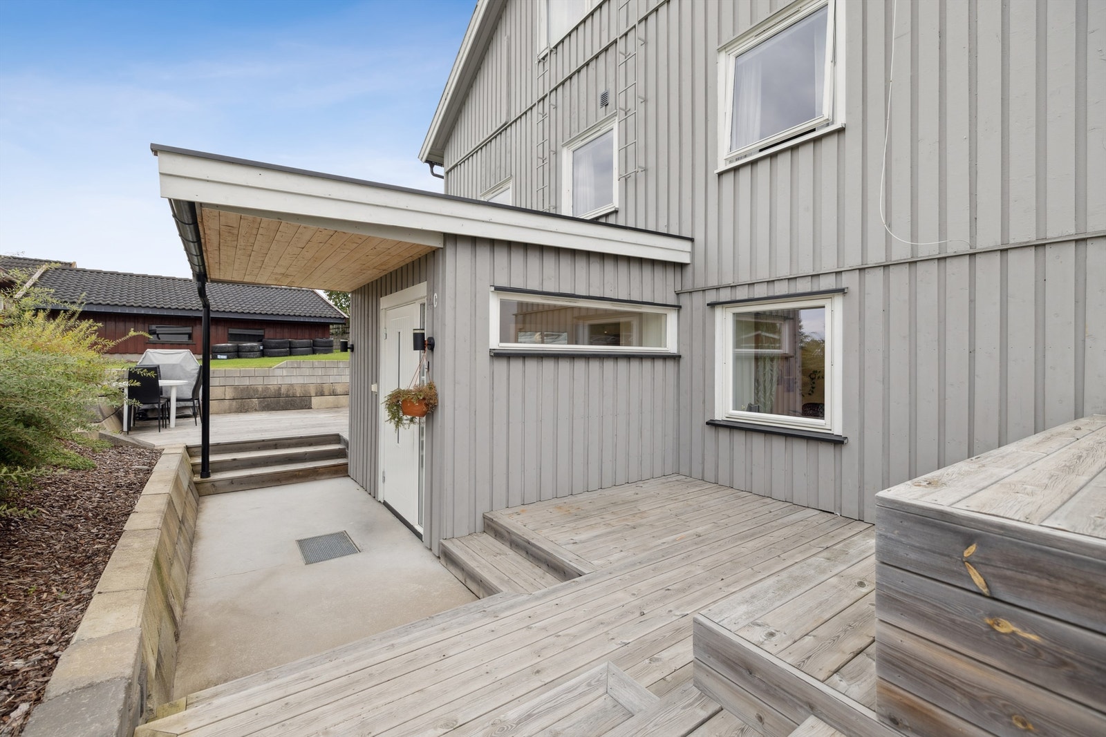 Nå beveger vi oss ut. Her ser vi det overbygde inngangspartiet og den store terrassen som hører til leiligheten. Galleribilde