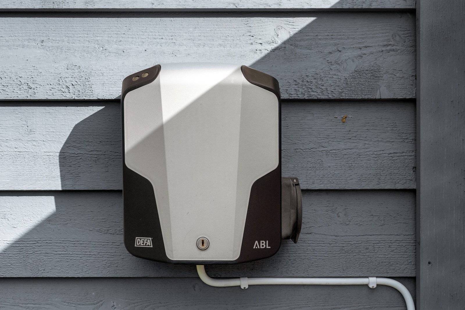 Det er lader for elbil på husveggen. Galleribilde