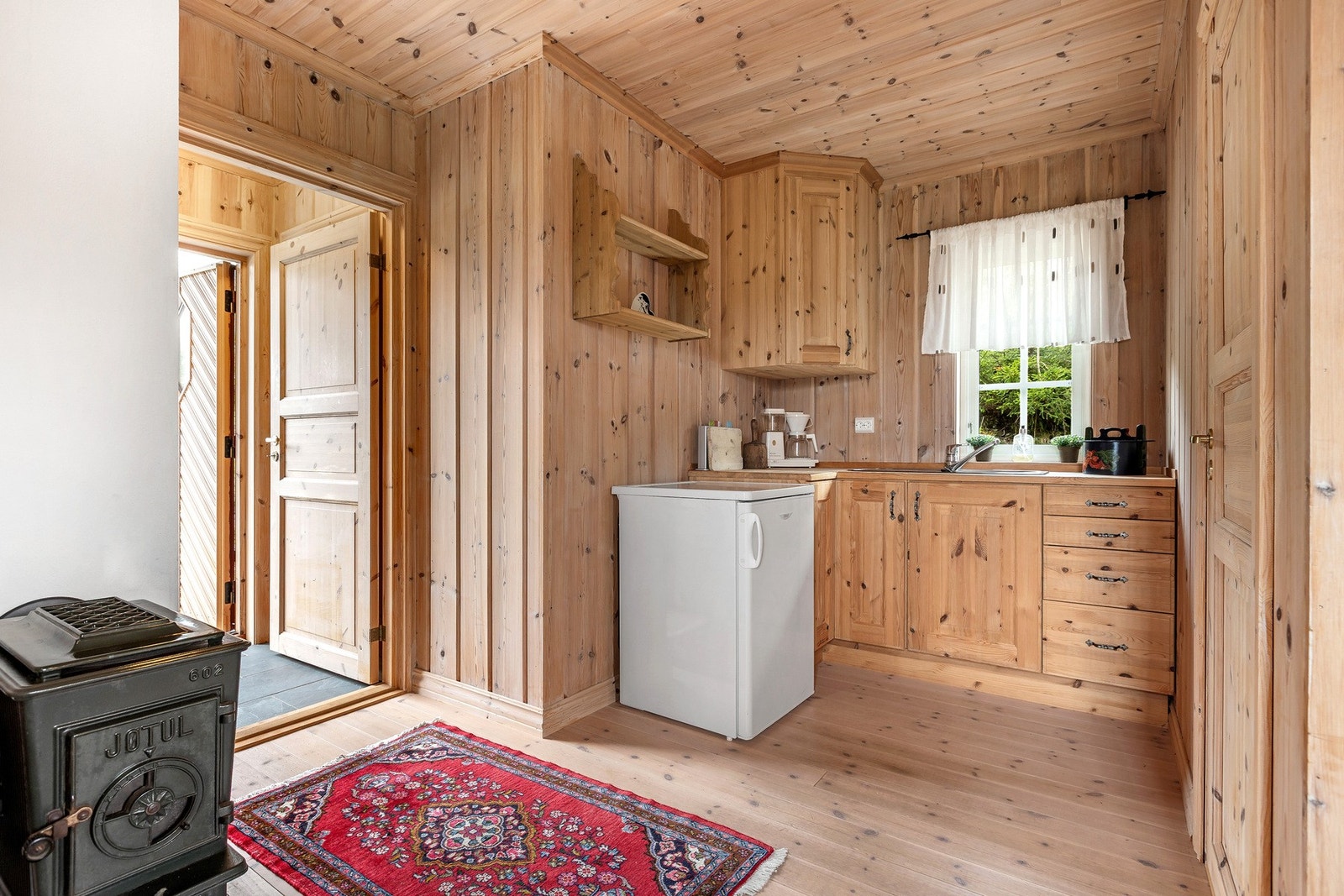 Kjøkkenkroken har heltre innredning med profilerte fronter og benkeplate, samt kjøleskap og naturlig avtrekk. Galleribilde