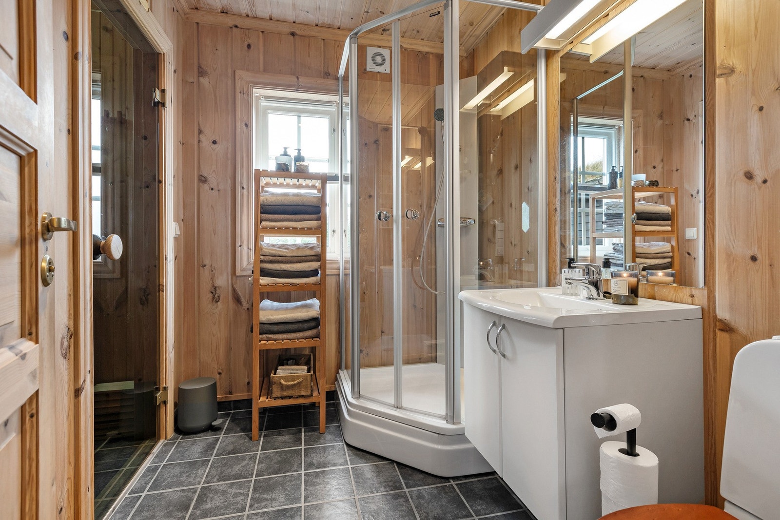 Lyst og praktisk baderom med panelte vegger, flislagt gulv og elektriske varmekabler for god komfort. Galleribilde