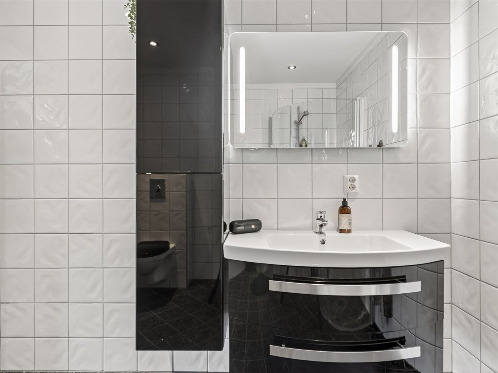 Her er en stilig buet innredning med skuffer og heldekkende servant, samt høyskap på siden. Speil på vegg med integrert belysning. Galleribilde