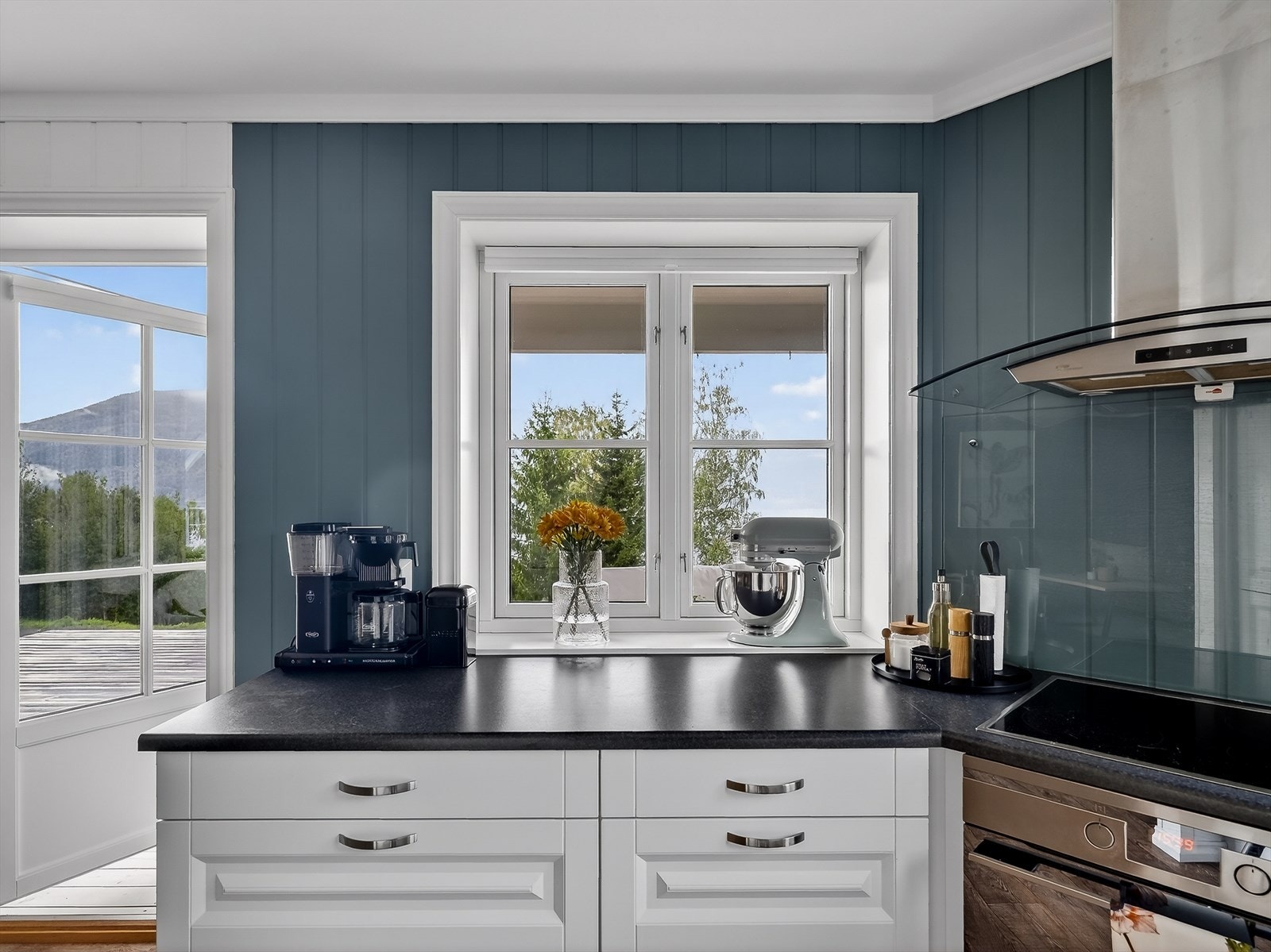 Glassplate på vegg ved koketoppen beskytter mot sprut og stekefett ved matlaging. Også her er det down-light belysning i tak. Galleribilde