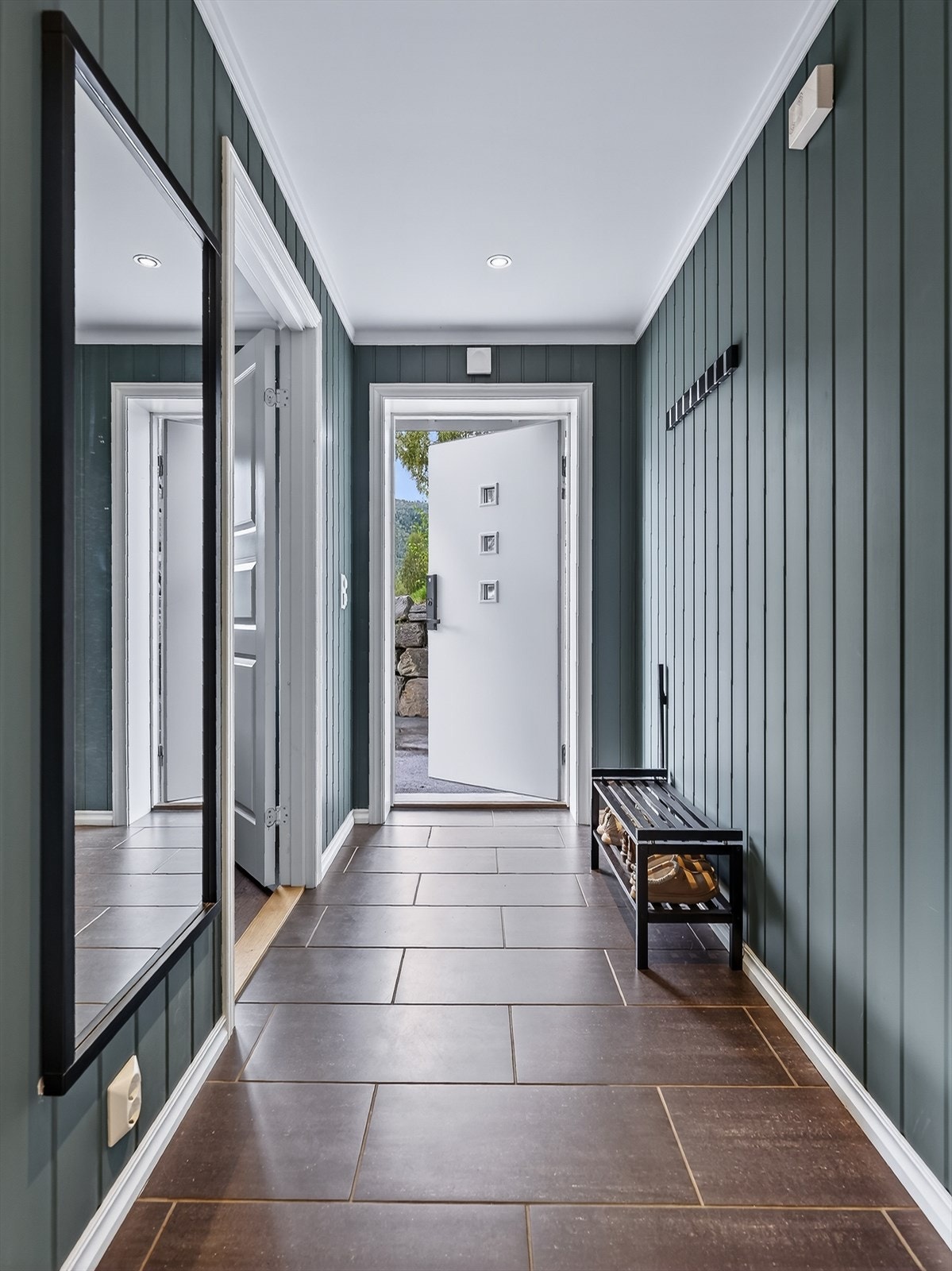 Leiligheten har et romslig gangareal med flislagt gulv og en lun fargetone på veggene. Galleribilde