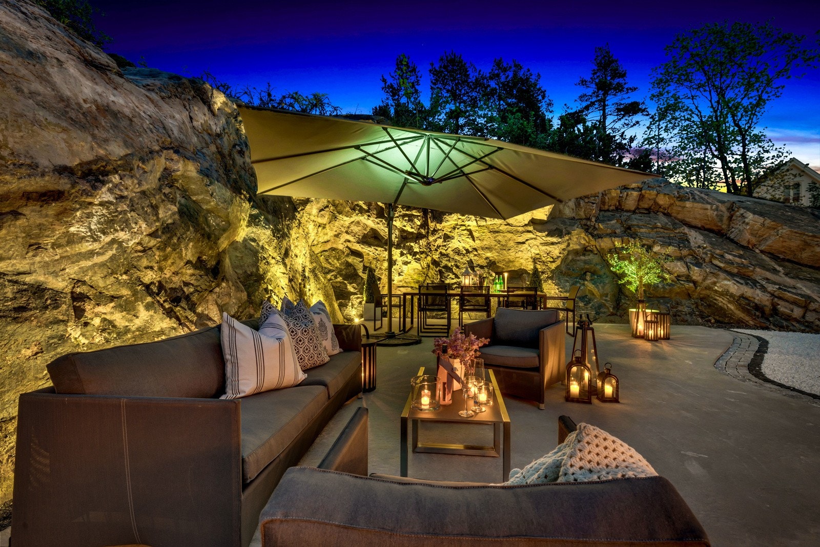 Uteplassen er stemningsfullt opplyst med kobberlamper og uplights langs fjellveggen. Galleribilde