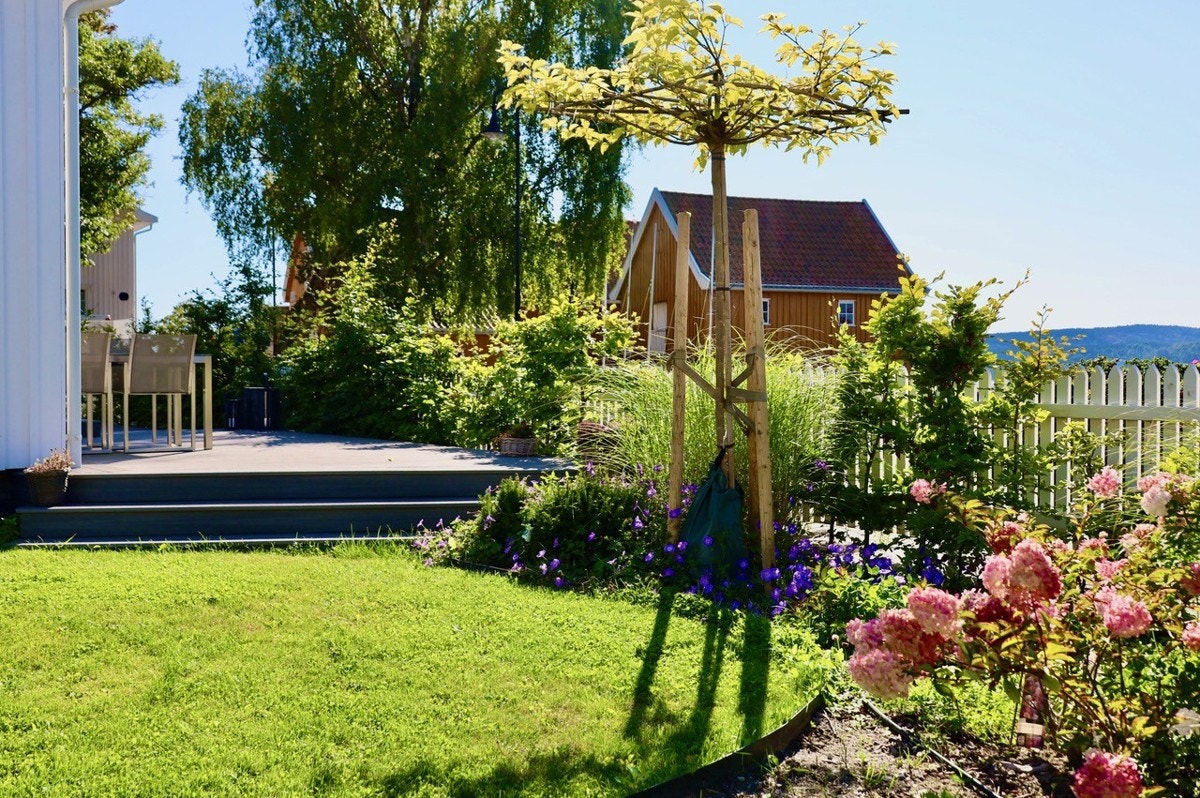 Hagen er pent opparbeidet med plen og beplantning, inngjerdet med hvitt stakittgjerde - perfekt arrondert til omgivelsene rundt. Galleribilde