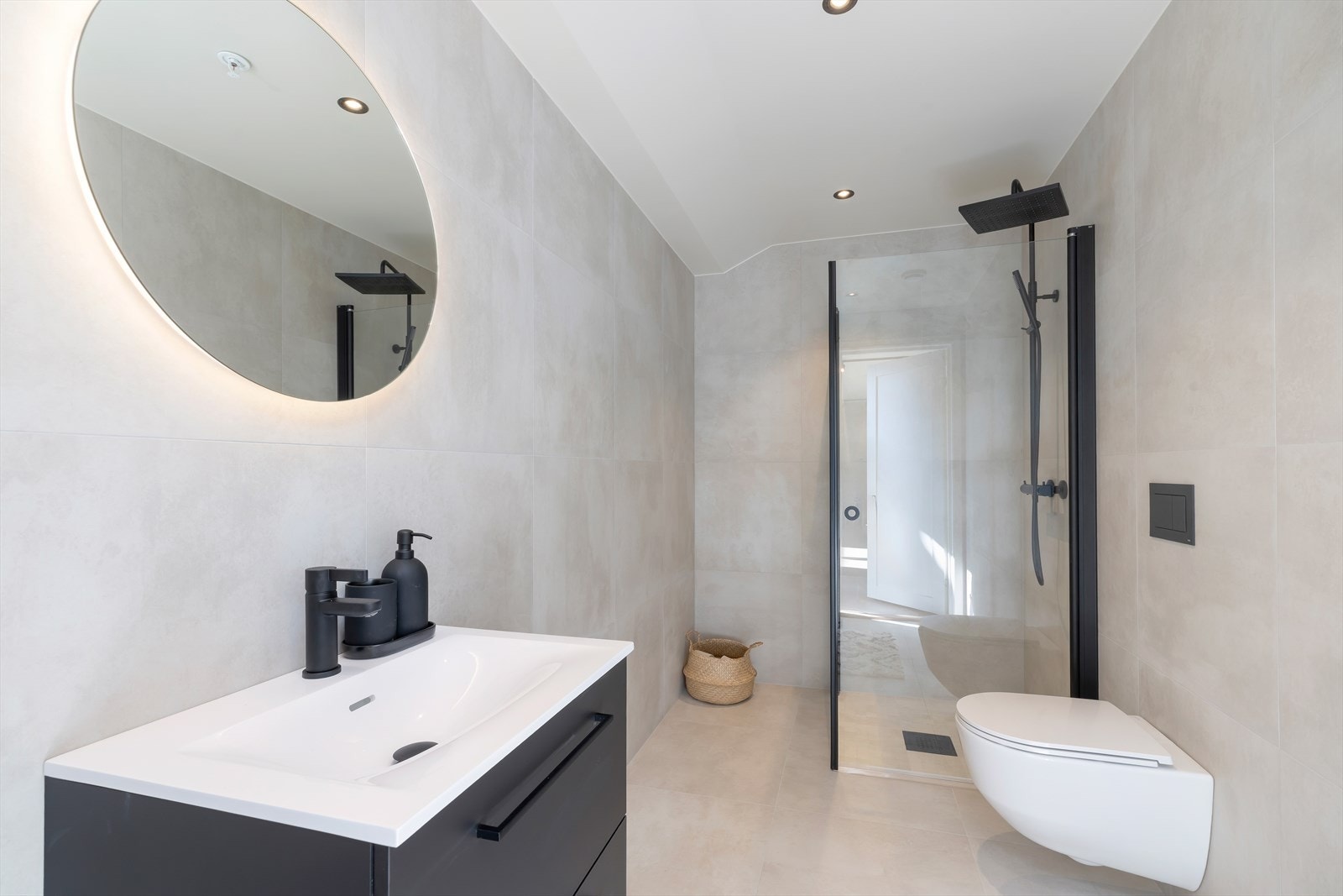 Delikat baderom med sorte detaljer, stemningsfull belysning i speil og takspotter som skaper en lun atmosfære Galleribilde