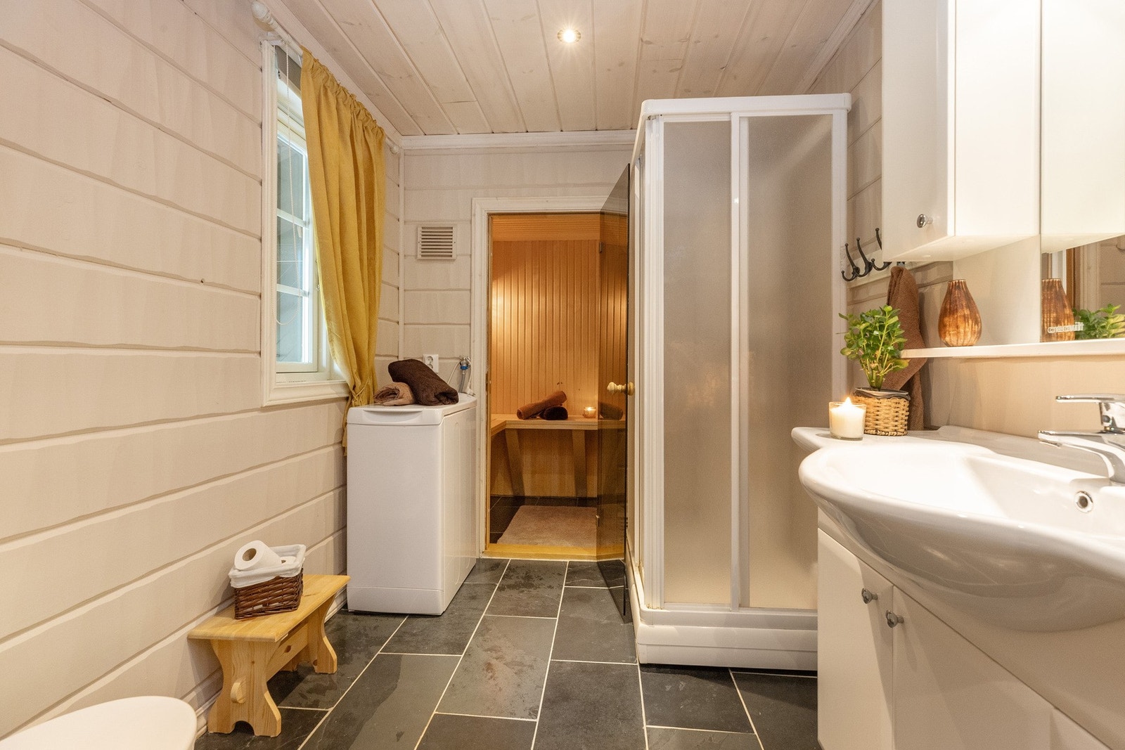 Badet i 1.etasje har toalett, dusjkabinett, servant med underskap og speil med speilskap. Her finnes også opplegg for vaskemaskin, og vaskemaskinen medfølger salget. Galleribilde