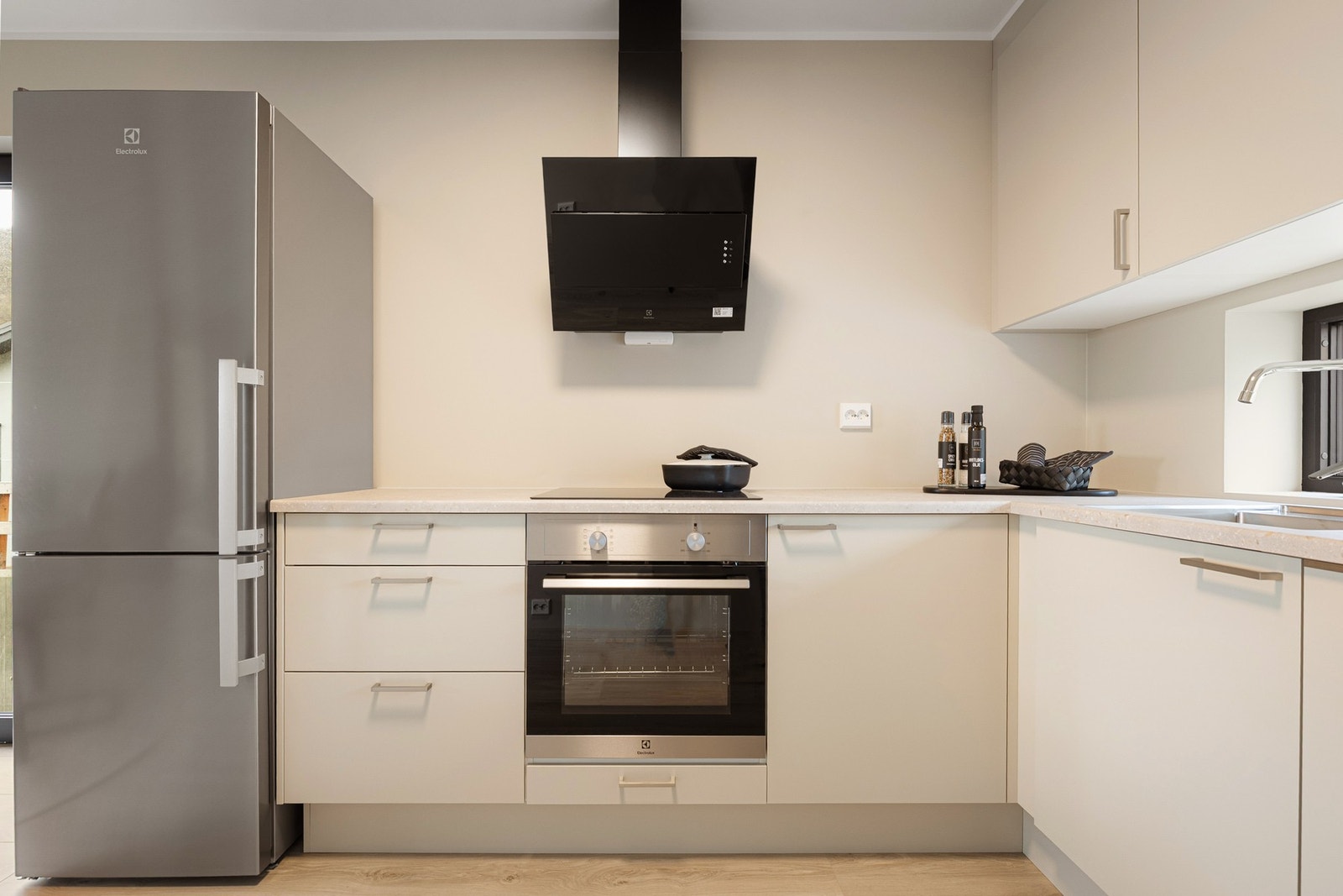 Stilrent kjøkken med glatte fronter og integrerte hvitevarer som induksjonstopp, stekeovn og oppvaskmaskin. Galleribilde