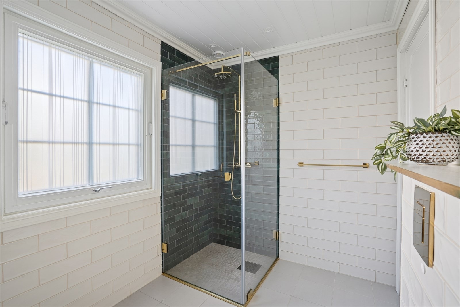 Dusjsonen har mørkegrønne fliser som gir en lekker kontrast med de hvite flisene i rommet. Galleribilde