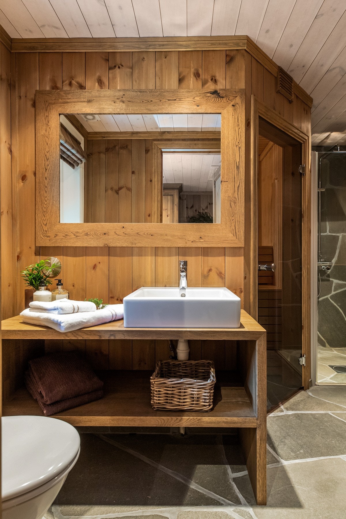 Hytta har to bad. Det ene badet inneholder baderomsinnredning i heltre med servant og åpne hyller under, toalett, dusjhjørne og badstue Galleribilde