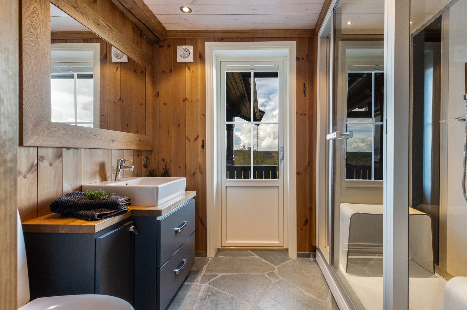 Dette badet inneholder baderomsinnredning med skuffer under benk, heltre benkeplate med servant, toalett og dusjnisje med steamdusj/steambadstue Galleribilde