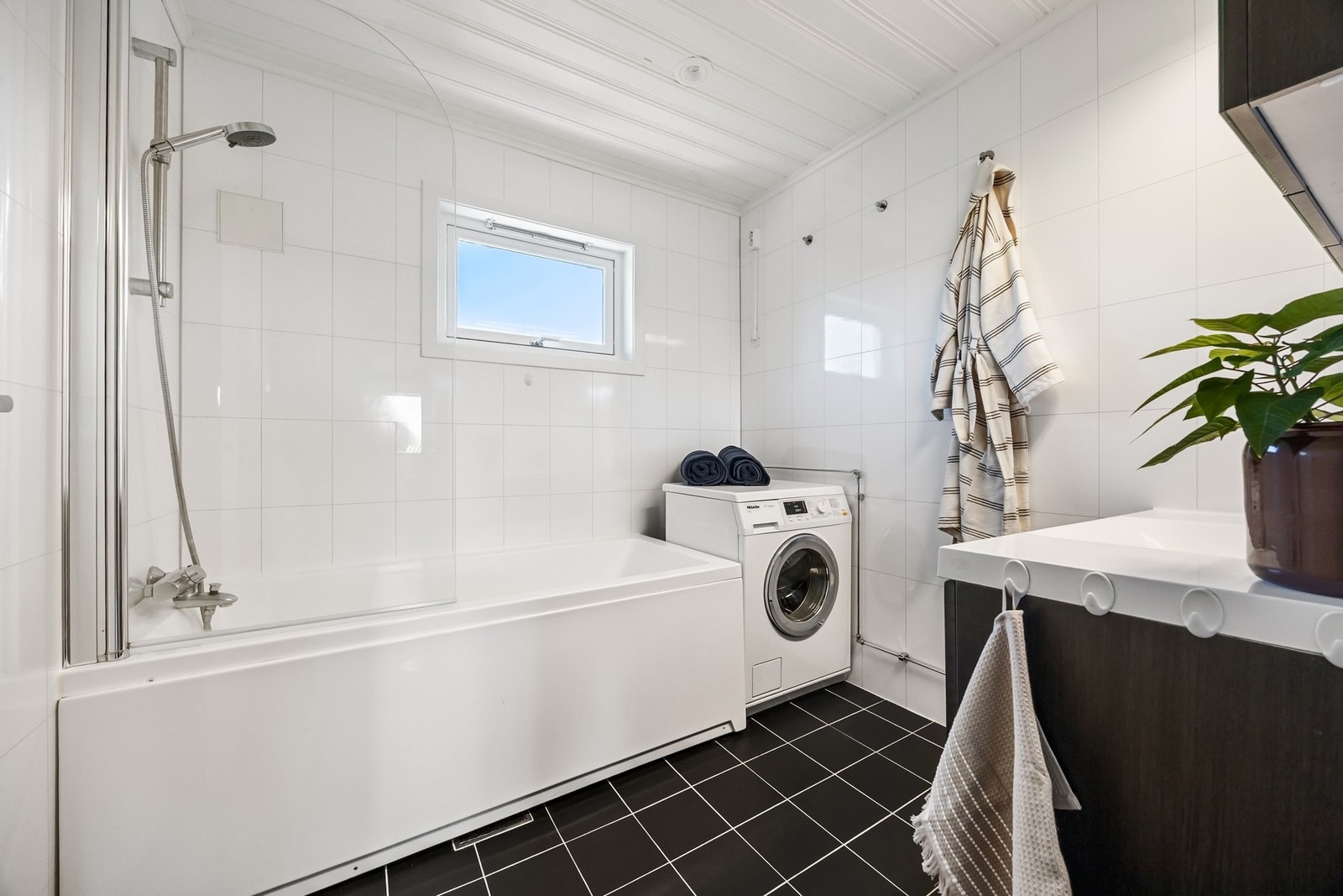 Baderom utstyrt med varmekabler, badekar med hånddusj og servantinnredning Galleribilde