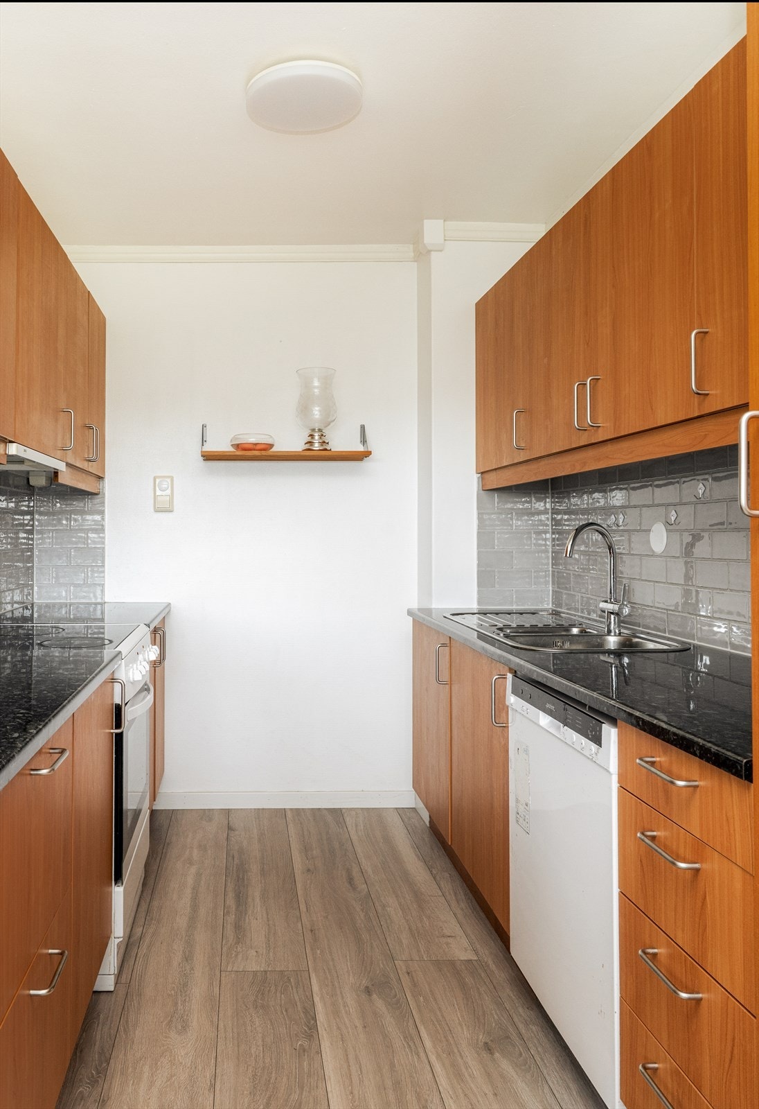 Slette fronter, laminat benkeplate og benkebeslag med dobbel stålkum med et-greps blandebatteri. Det er frittstående kjøl/fryseskap, oppvaskmaskin og komfyr. Galleribilde