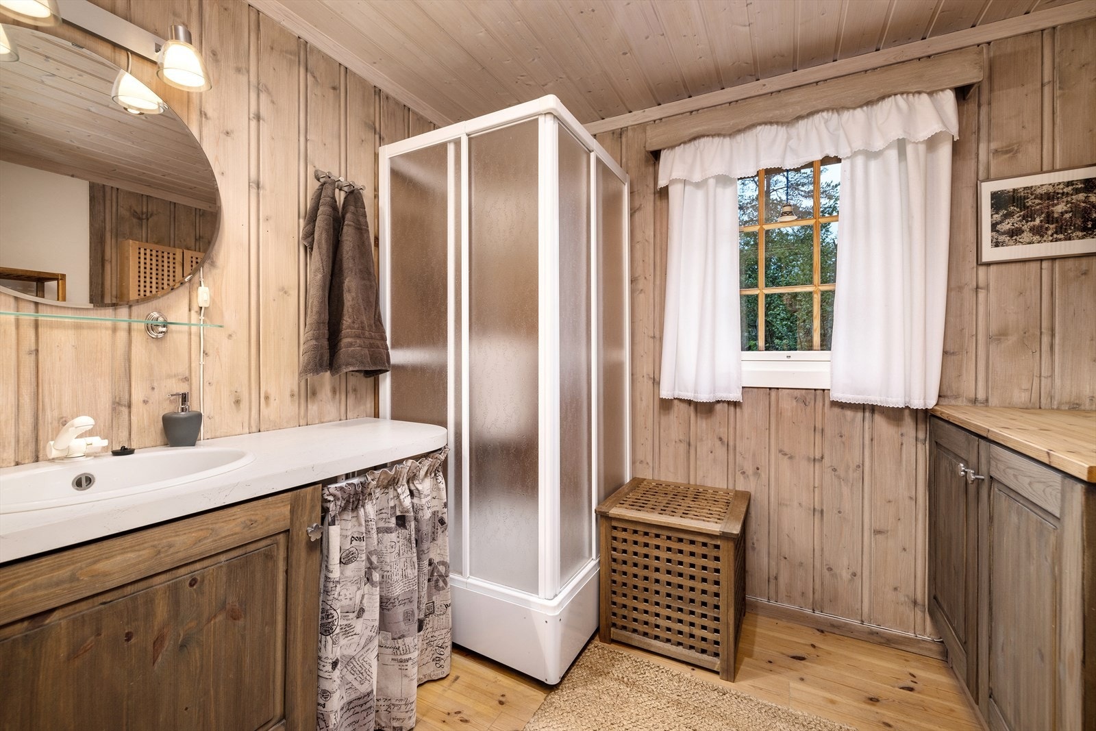Baderom med furugulv, panel på vegger og tak. Det er installert dusjkabinett og innredning med servant. Galleribilde