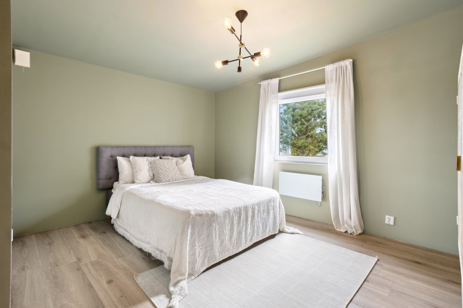 Panelovn montert under vindu som varmekilde, og det er montert garderobeskap langs en vegg Galleribilde