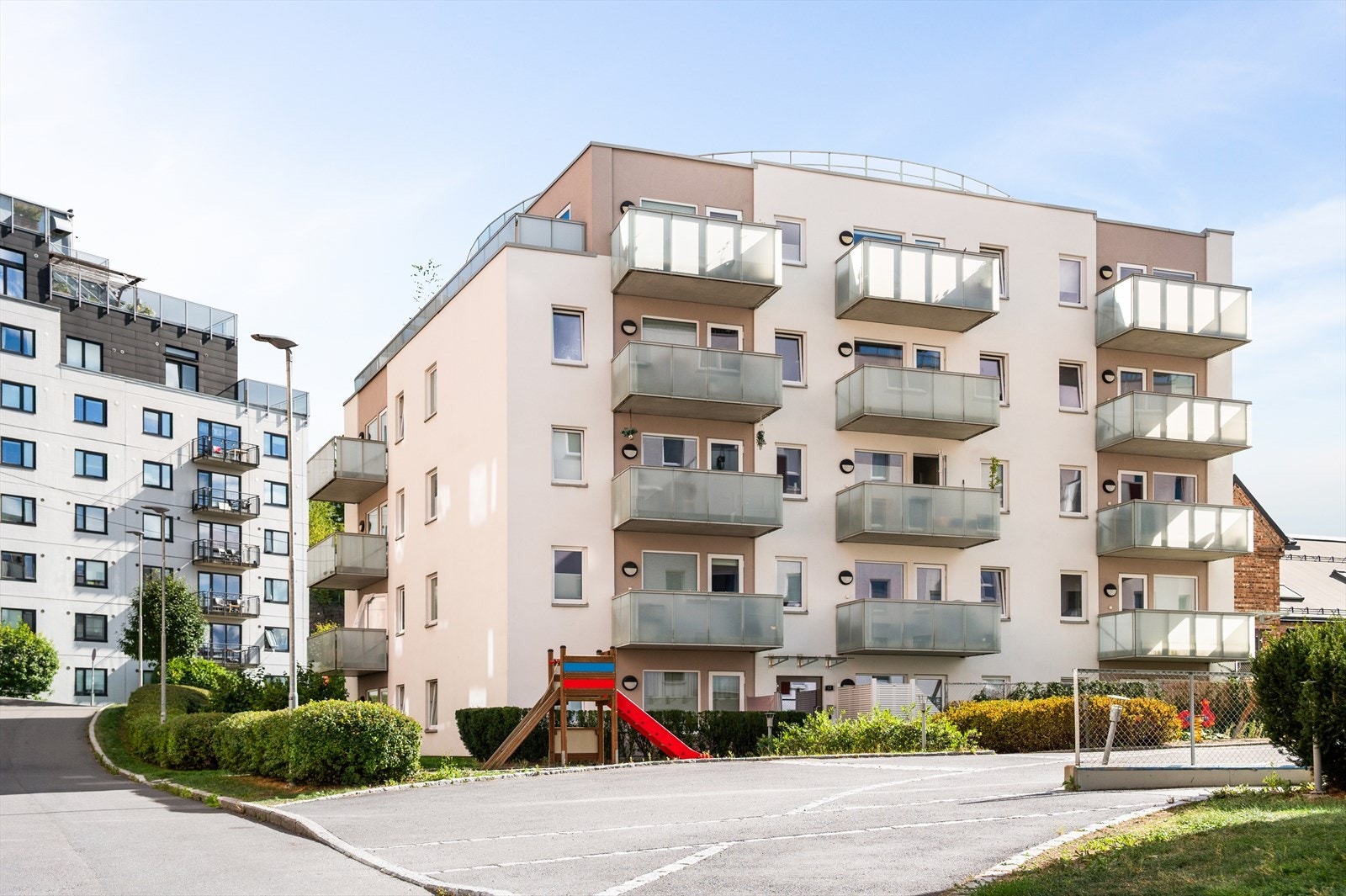 Fasade og fellesområder pent opparbeidet med lekeapparater, gangstier og beplantning. Galleribilde