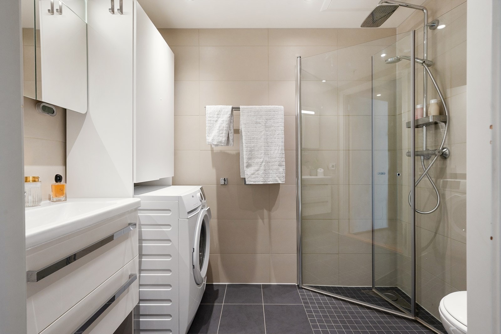 Pent og tidsriktig baderom fra byggeår, innredet med dusjhjørne med innfellbare glassdører, vegghengt toalett og servant med skuffer som gir god oppbevaringsplass. Galleribilde