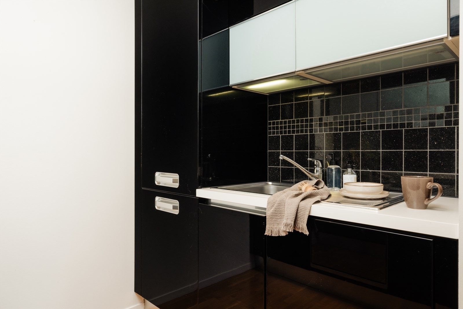 Kjøkkeninnredning med folierte skrog, slette fronter sort høyglans fronter og laminert benkeplate. Galleribilde