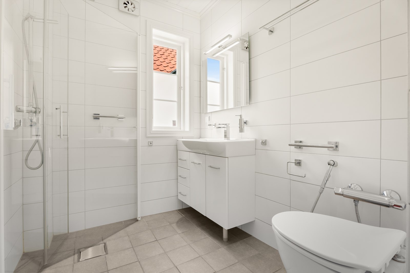 Huset har 2 romslige bad. Dette er det første badet, oppgradert i 2010 med fliser, vegghengt toalett og dusjhjørne med glassdører. Galleribilde