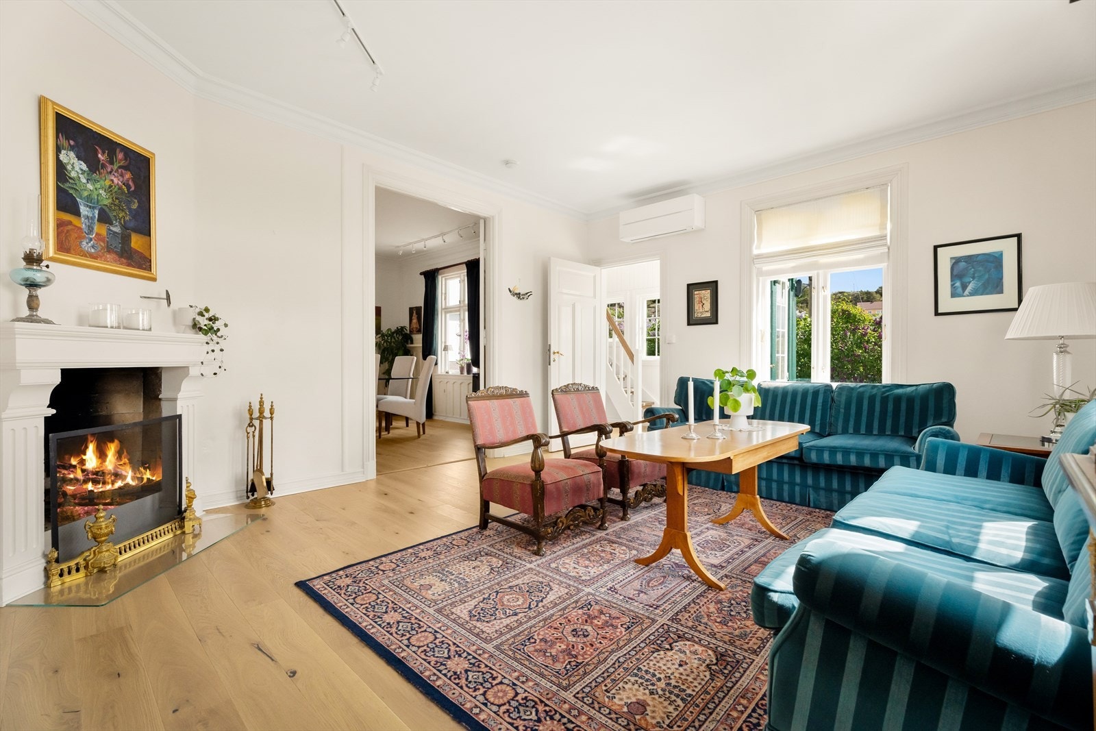 Velkommen inn i en lys og innbydende stue med god takhøyde og klassisk åpen peis som skaper lun stemning i vintersesongen. Galleribilde