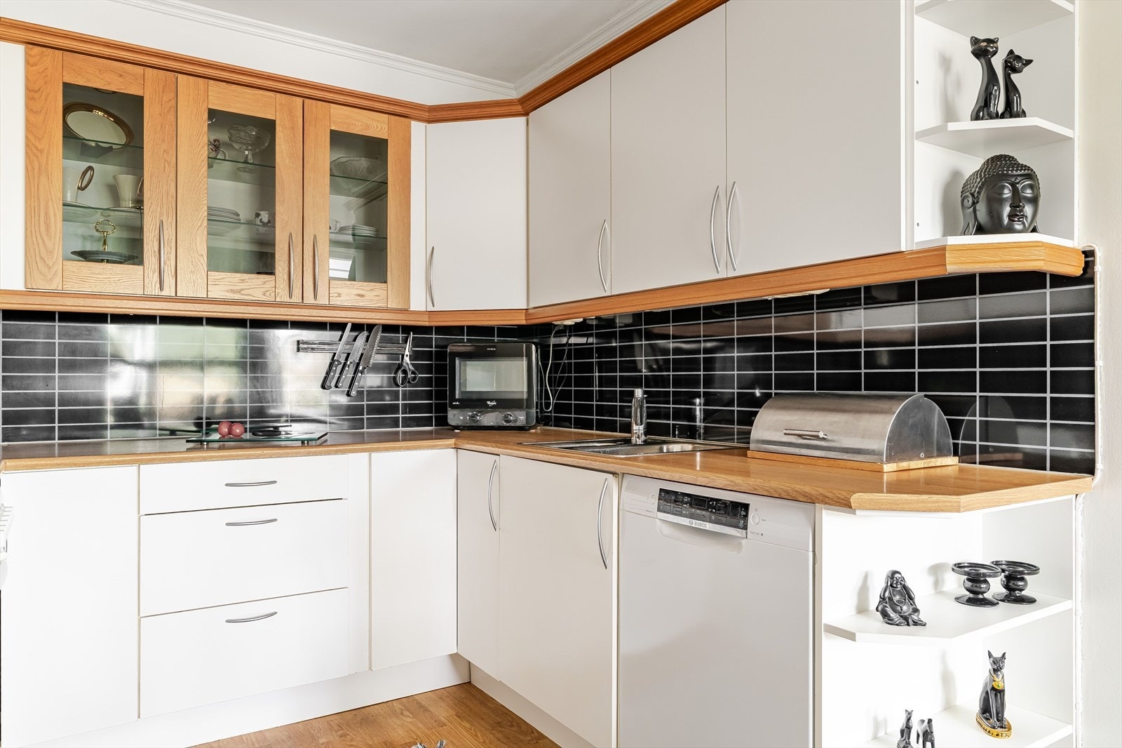 Det er rikelig med skapplass, overskap med glassdører og mørk flisvegg som skaper en fin kontrast. Et kjøkken med karakter. Galleribilde