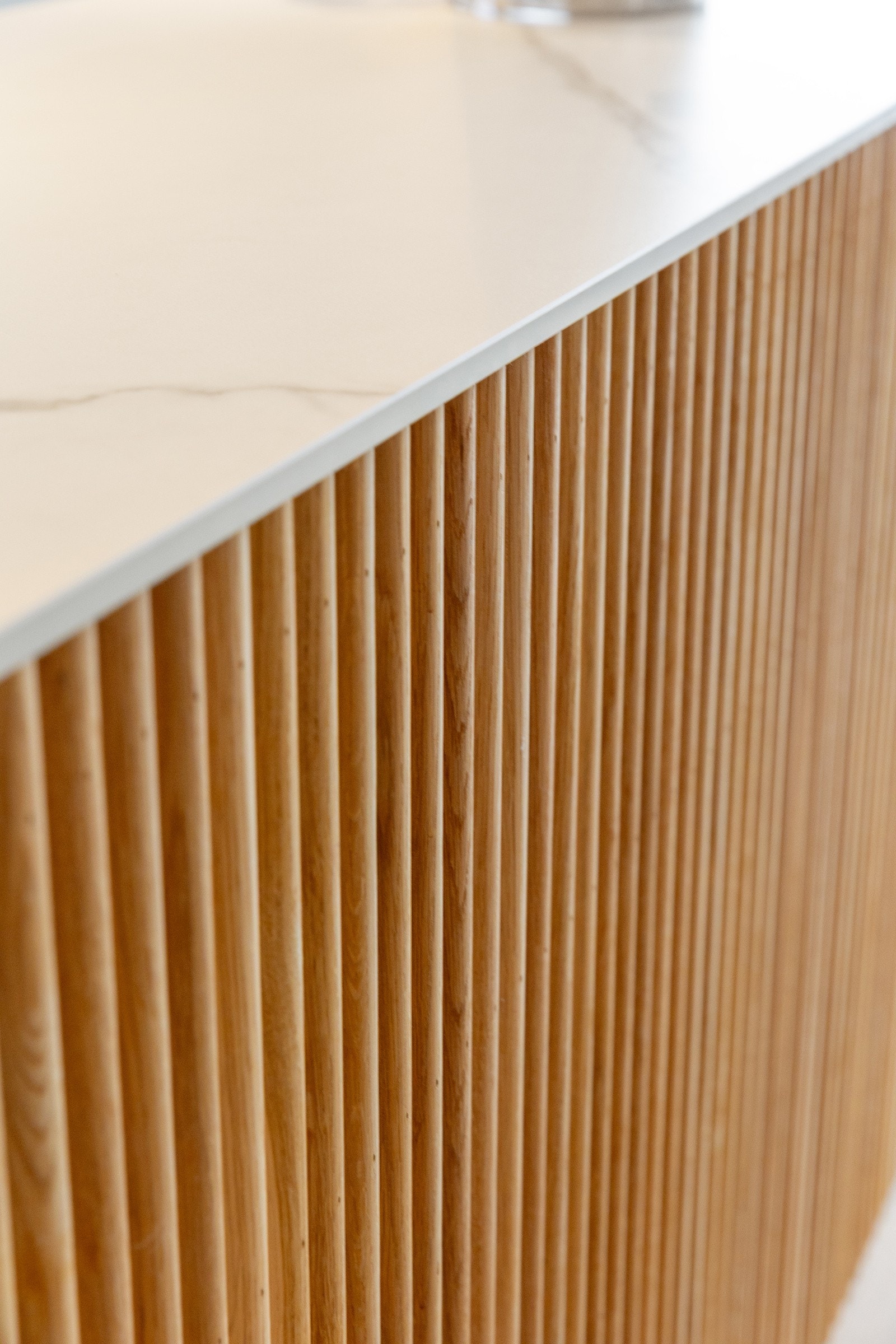 Kjøkkenet har mørke fronter og kjøkkenøy med spileverk Galleribilde