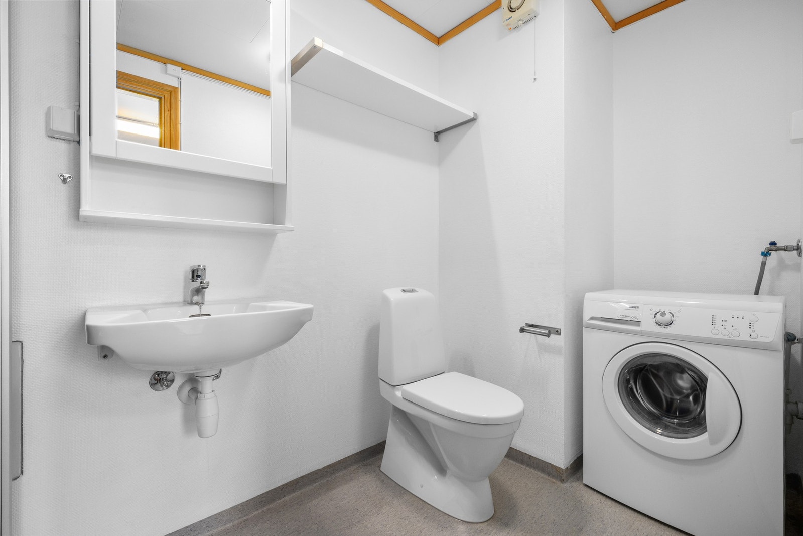 Badet inneholder servant og speilskap, toalett, dusjkabinett og nisje for vaskemaskin og tørkrtrommel. Galleribilde