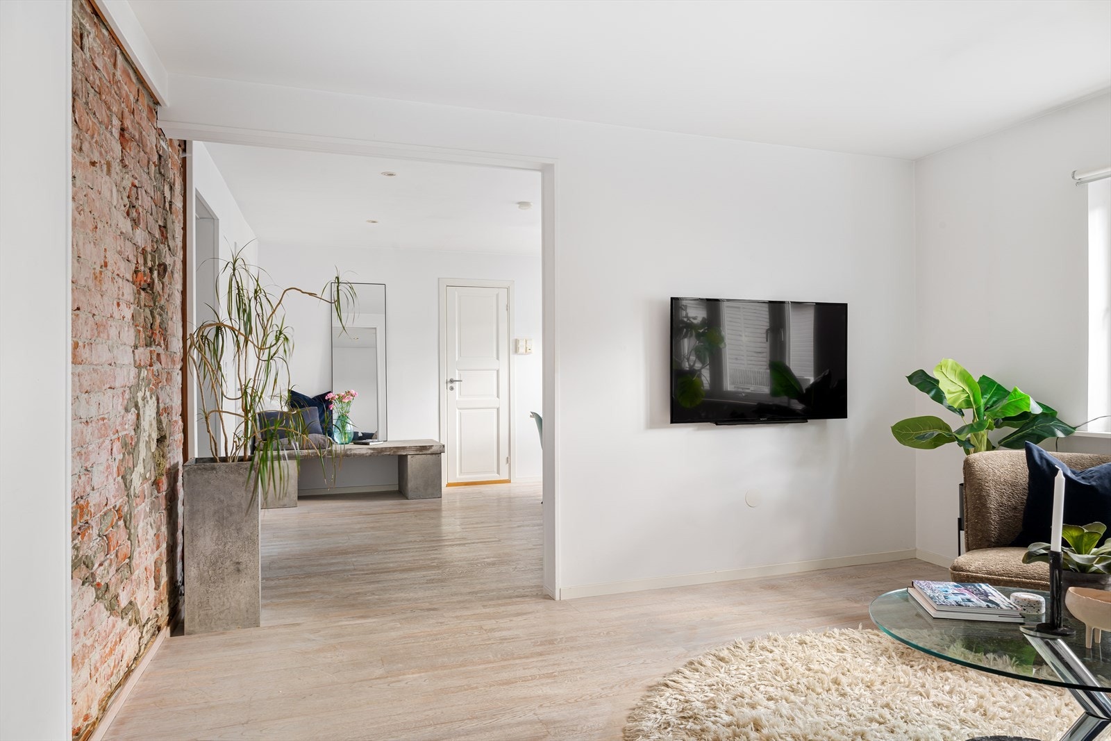 Lys og luftig stue med synlig murvegg som gir rommet et røft og moderne preg. Galleribilde