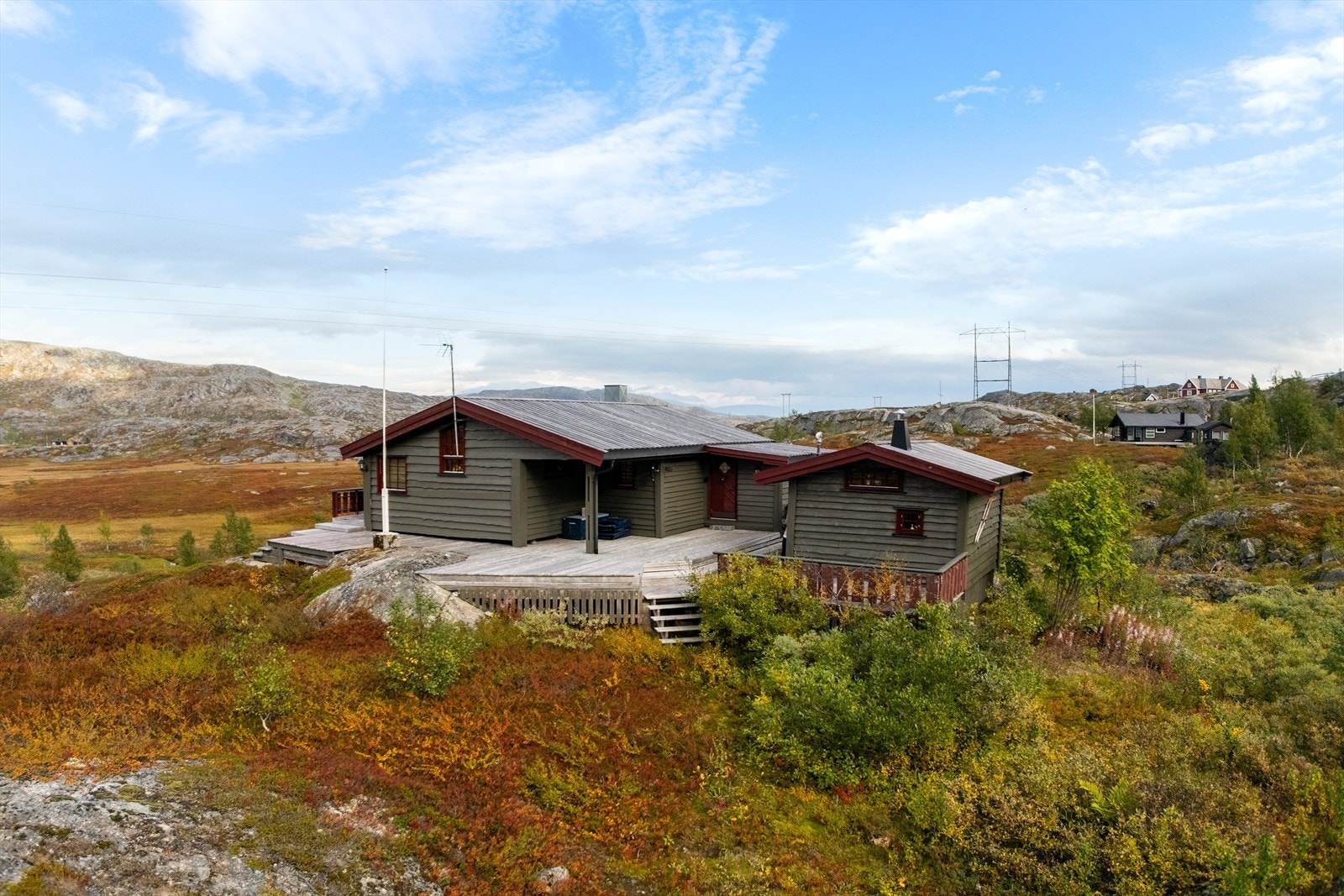 Hytta ligger fint til i terrenget med stor veranda og flott utsikt over fjellandskapet Galleribilde