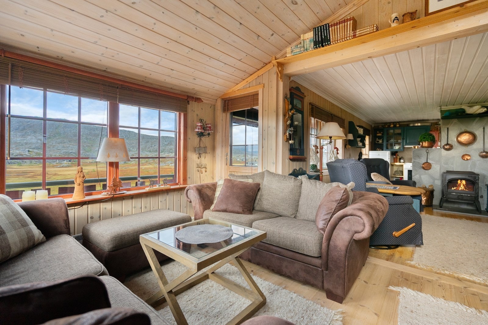 Stuen byr på en åpen og innbydende atmosfære, med utsikt og vedfyring som setter prikken over i-en på hytteopplevelsen Galleribilde