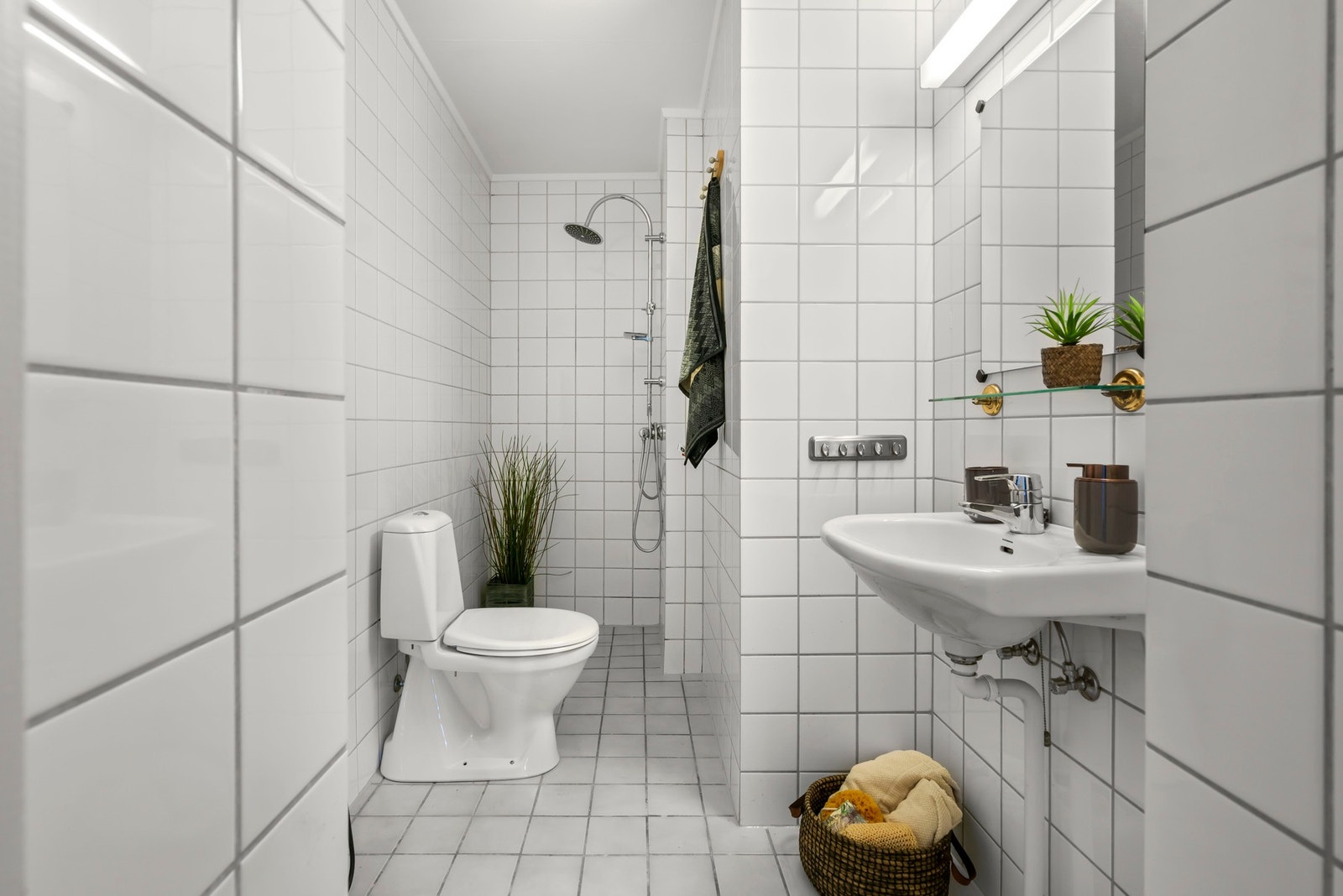 Pent flislagt bad, som er utstyrt med opplegg for vaskemaskin, toalett, dusj og servant Galleribilde