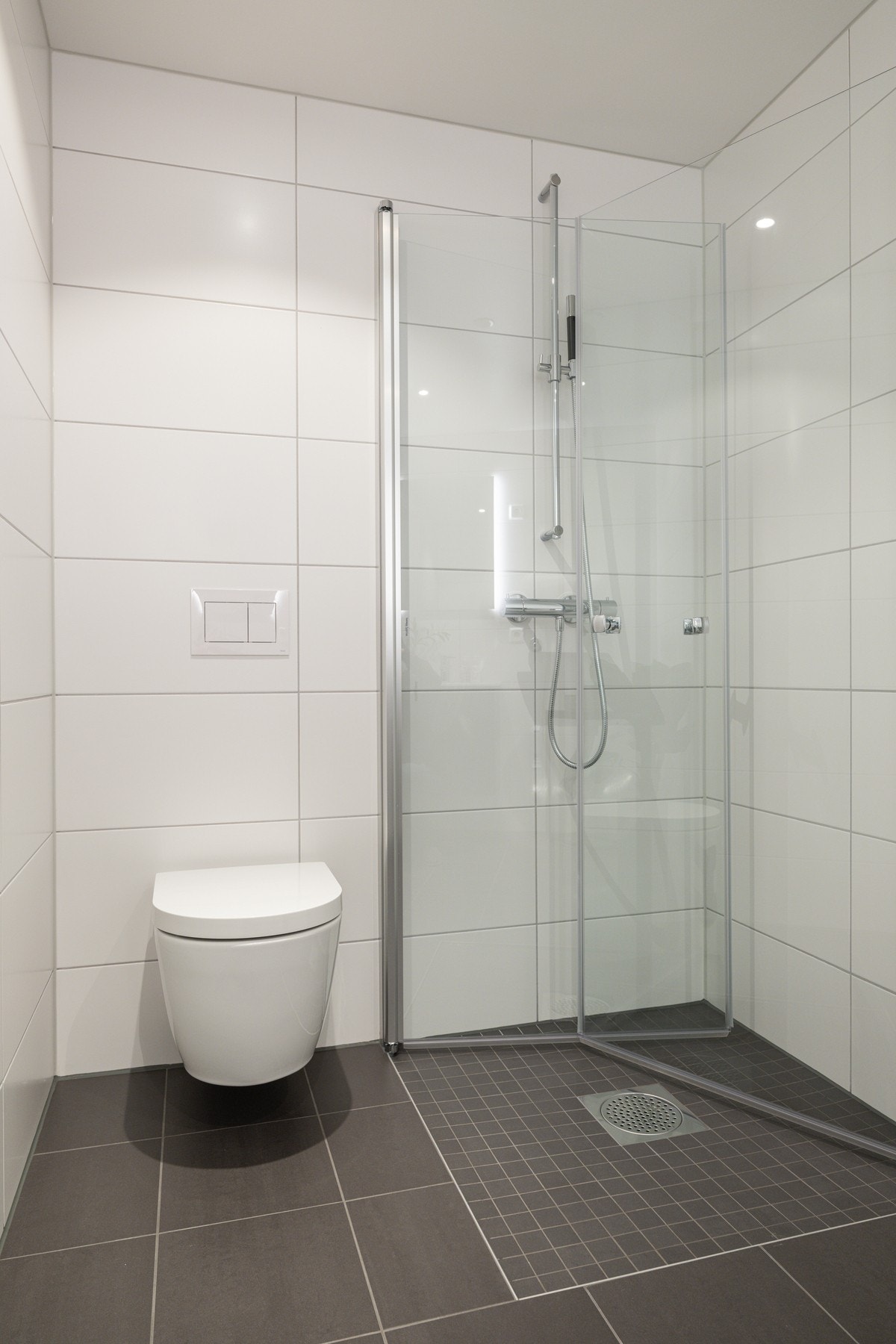 Videre en vegghengt wc og dusjnisje bak dører i glass. Galleribilde